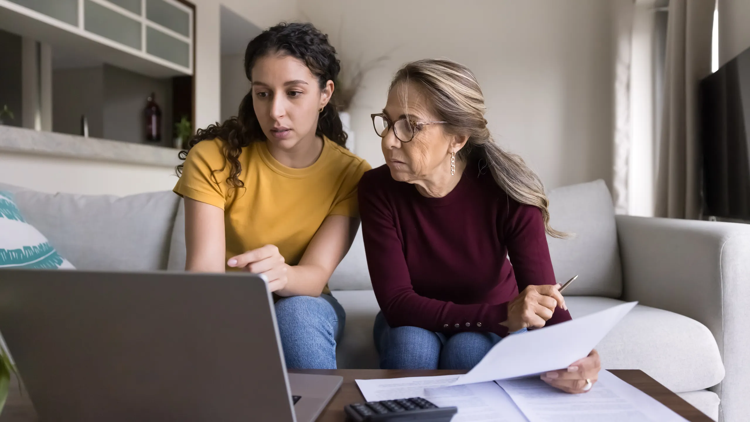 Focused Latin young daughter helping senior mother