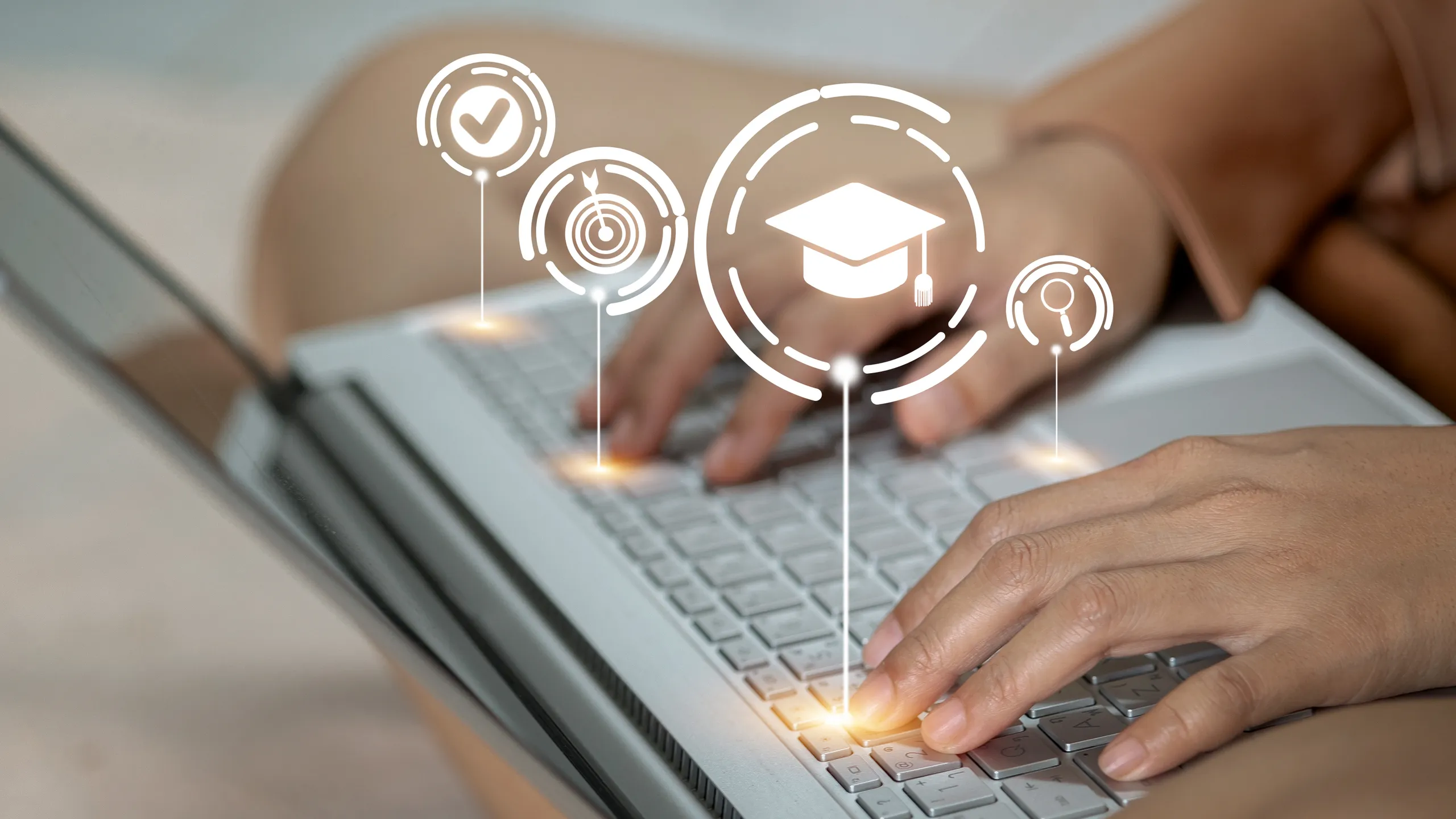 A woman is typing on a laptop with a graduation cap on the screen