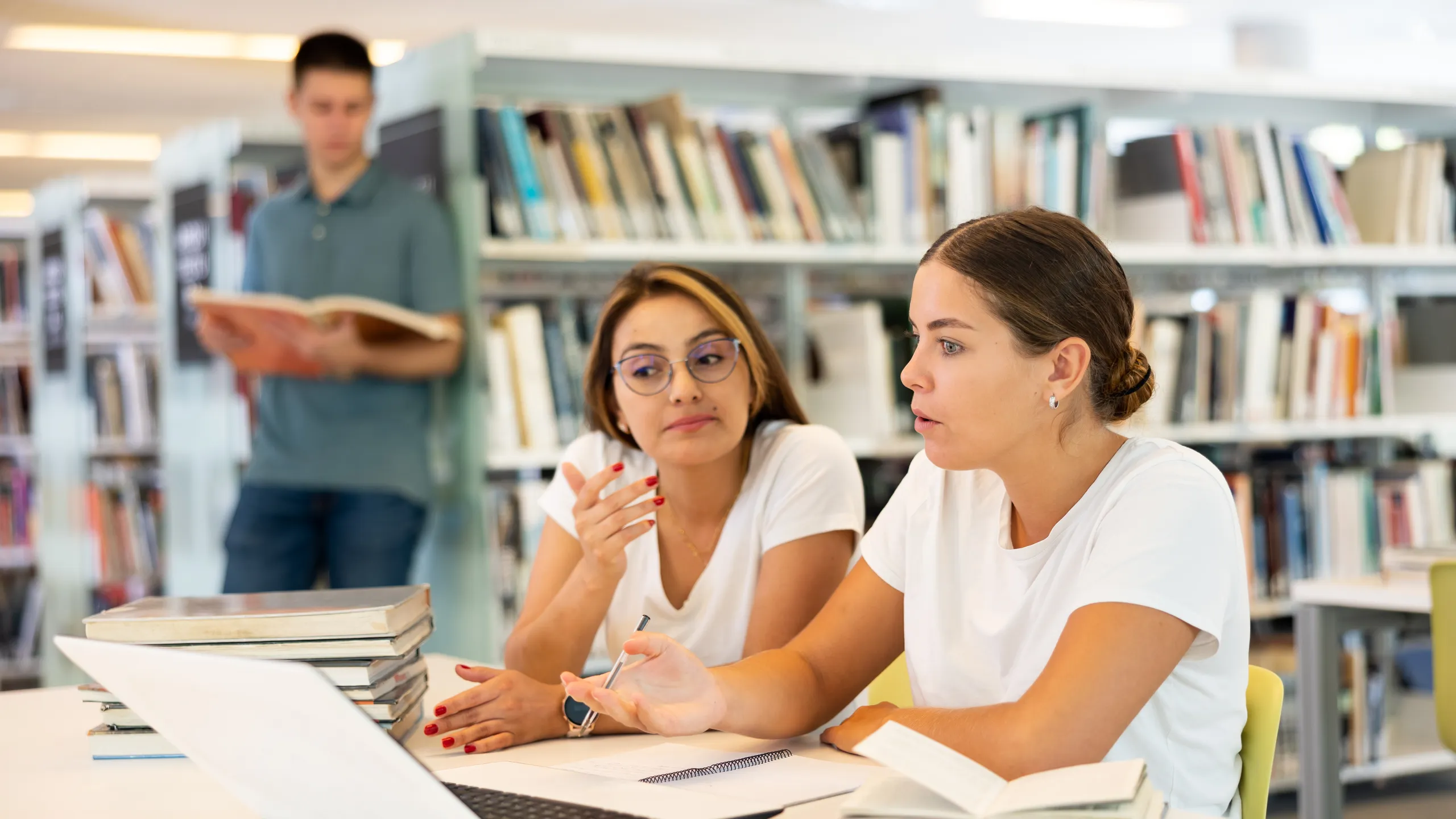 Skilled female students research together in library
