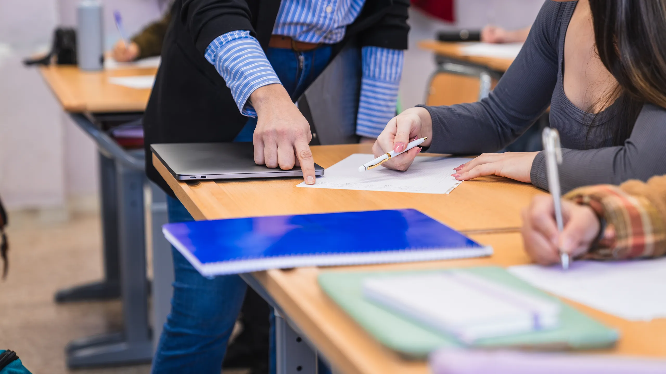 Teacher helping student during exam in high school classroom