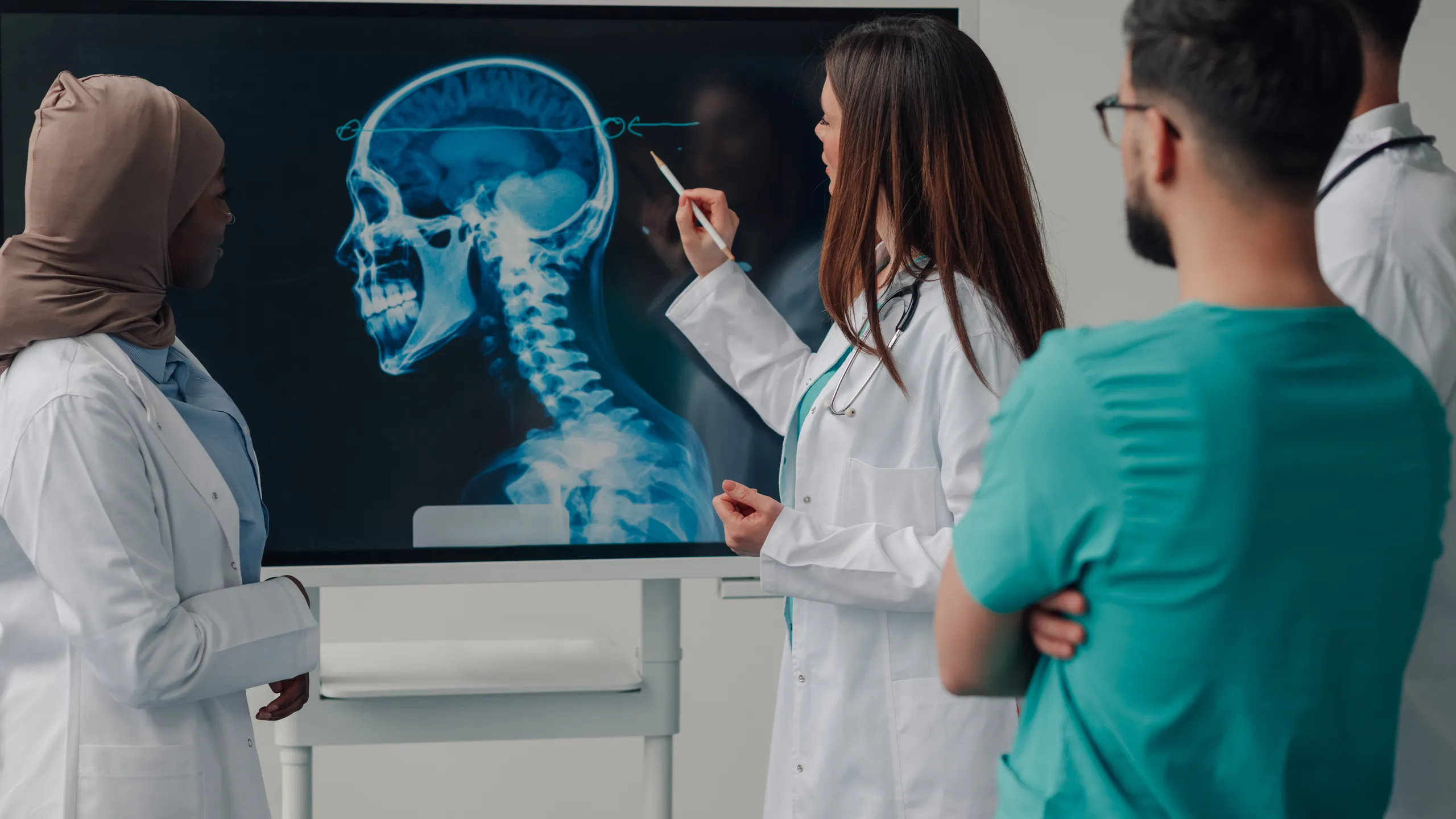 Medical team examining a skull x ray on a digital display