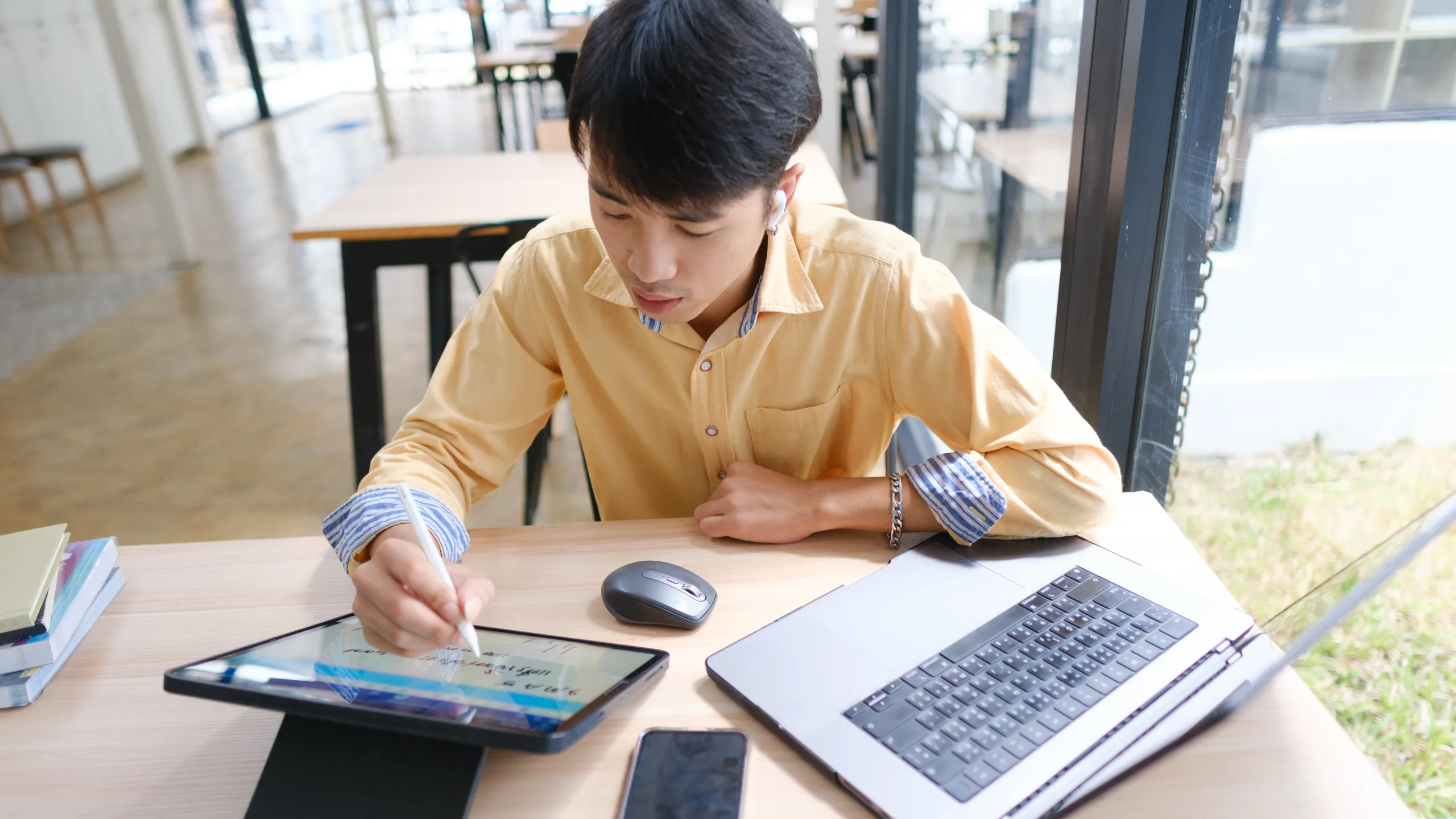 Student studying online and preparing for exams with digital devices and books