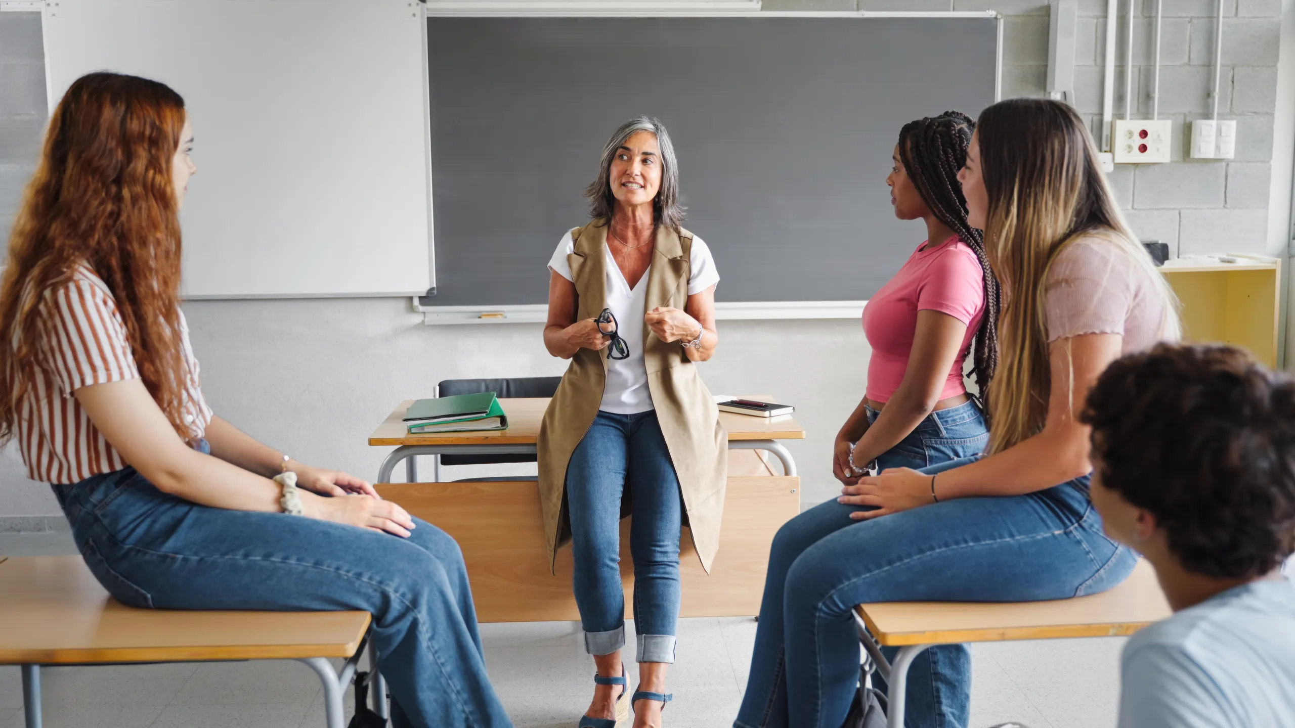 Teenager student class and senior female teacher sharing group support discussion at High School