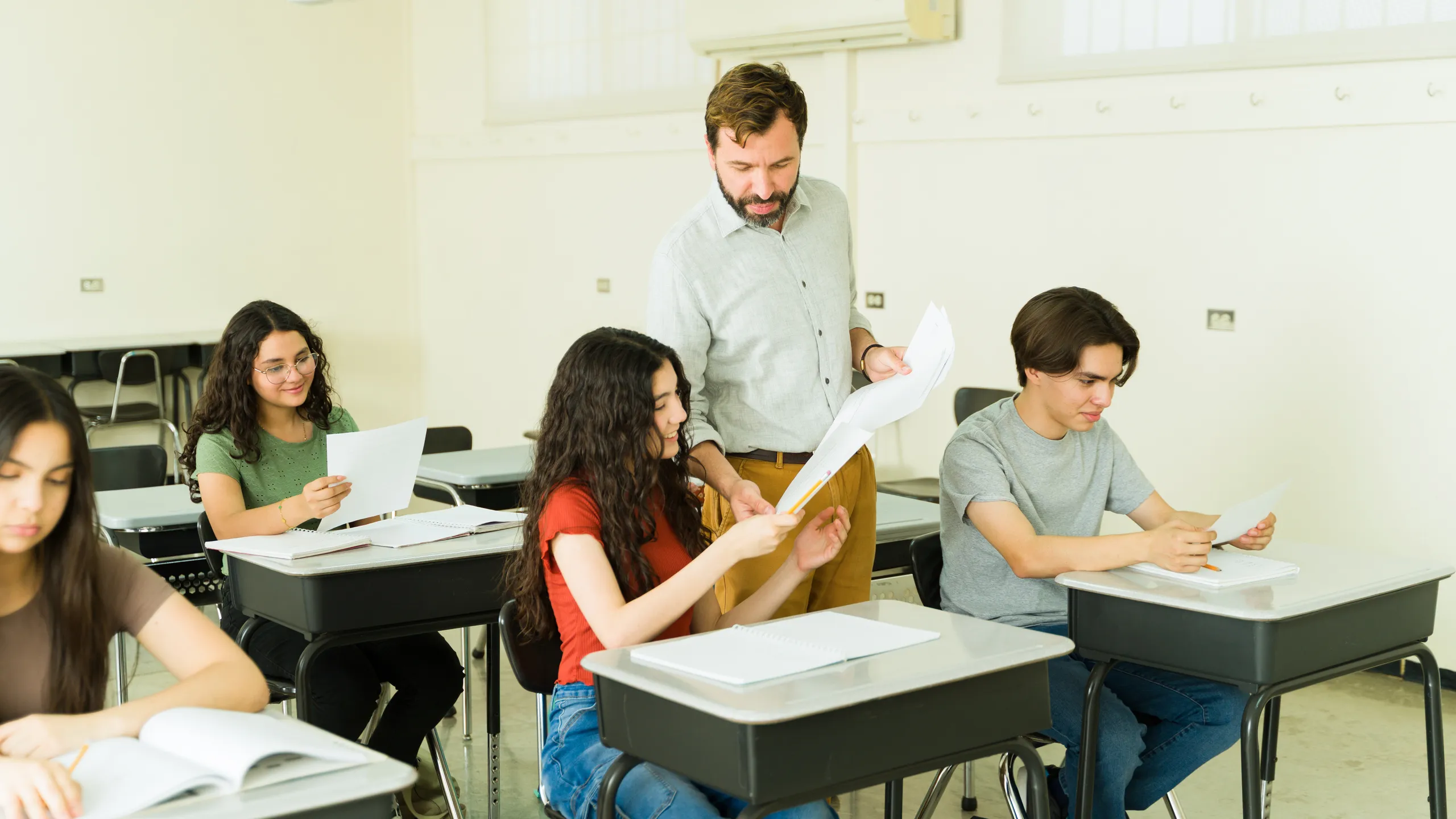 Teacher helping high school student with exam in classroom