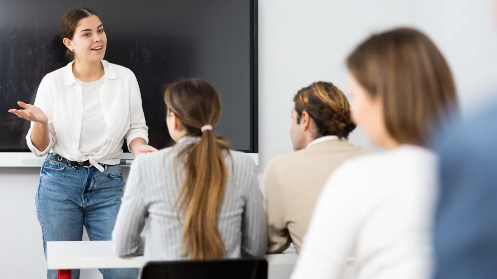 Young female professor explaining subject to classroom full of students
