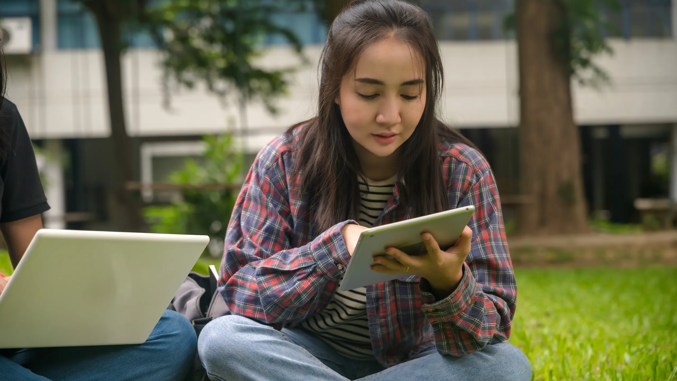 Young Asian female college student working with tablet in campus