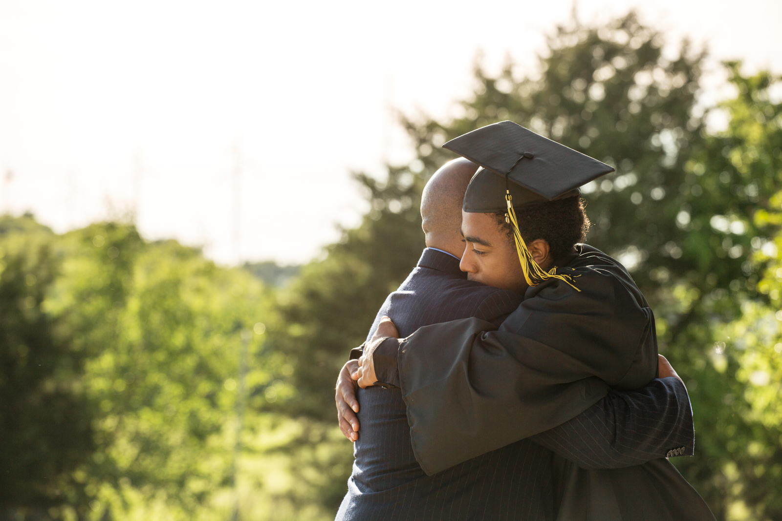 Parent hugging his son at high school graduation, providing support without overstepping
