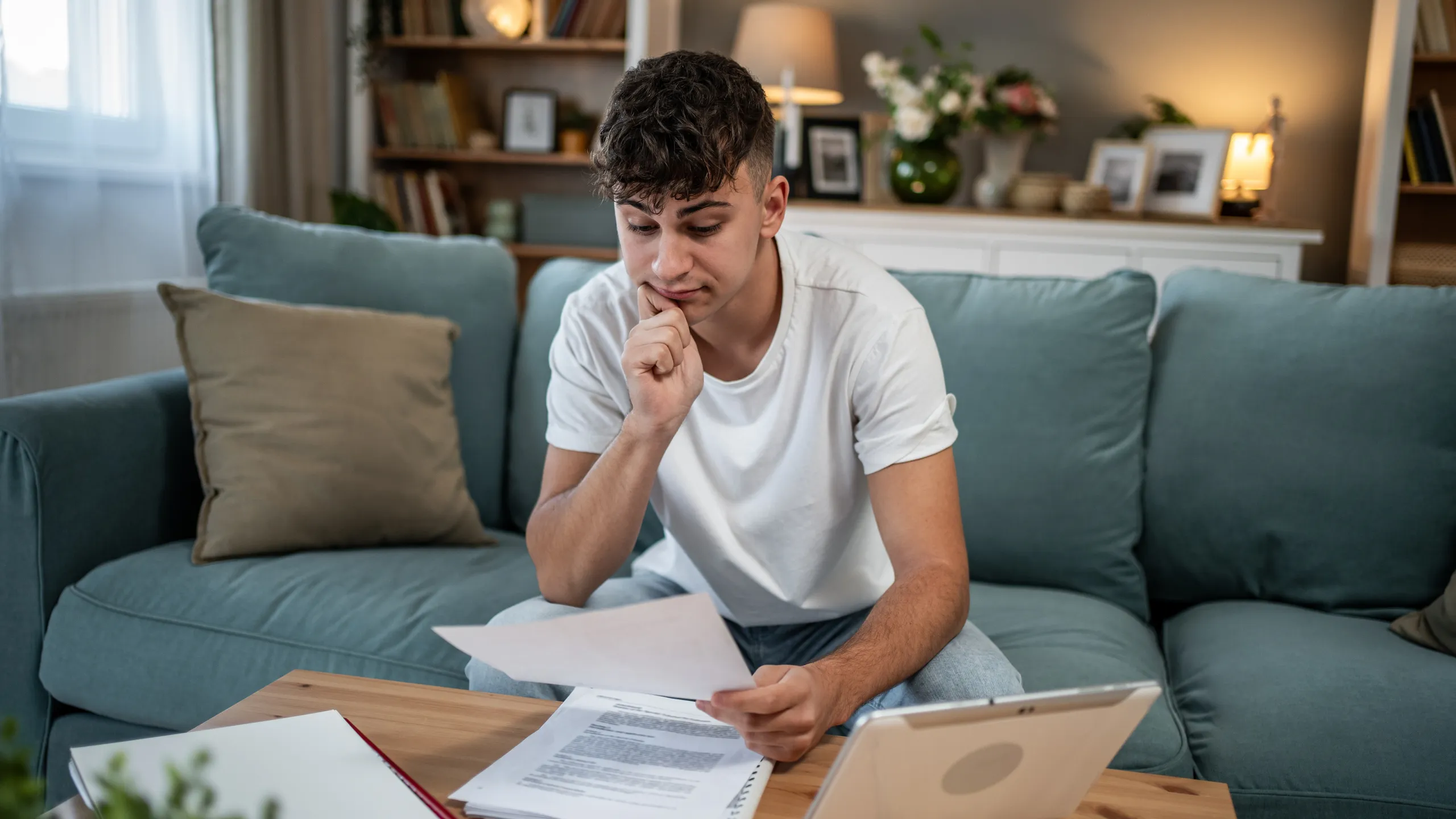 Young man feeling financial stress studying bills at home