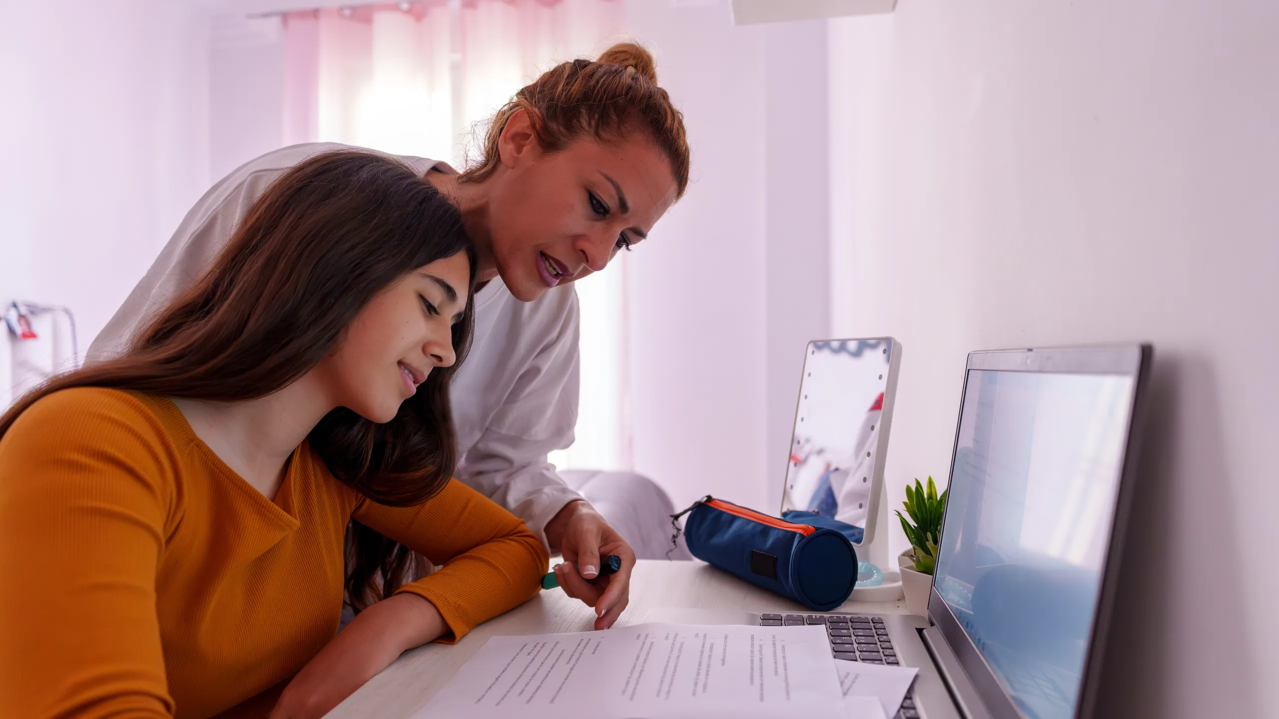 Mother assisting teenage daughter studying at home, providing guidance for school education and academic development