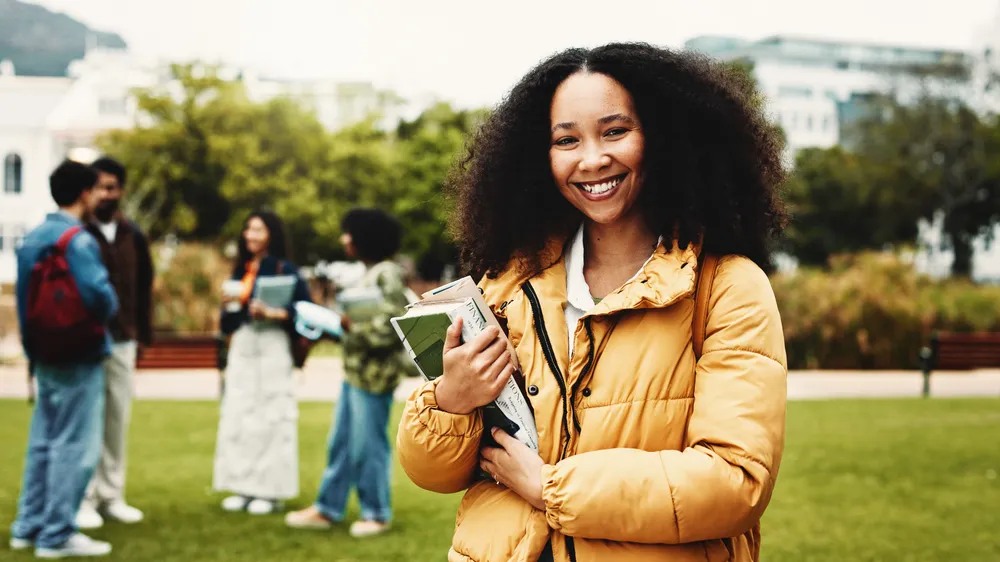 Portrait, student or woman on campus with textbook for college scholarship, education or english degree. Happy, person outdoor or books at university for literature study, knowledge or academic goals