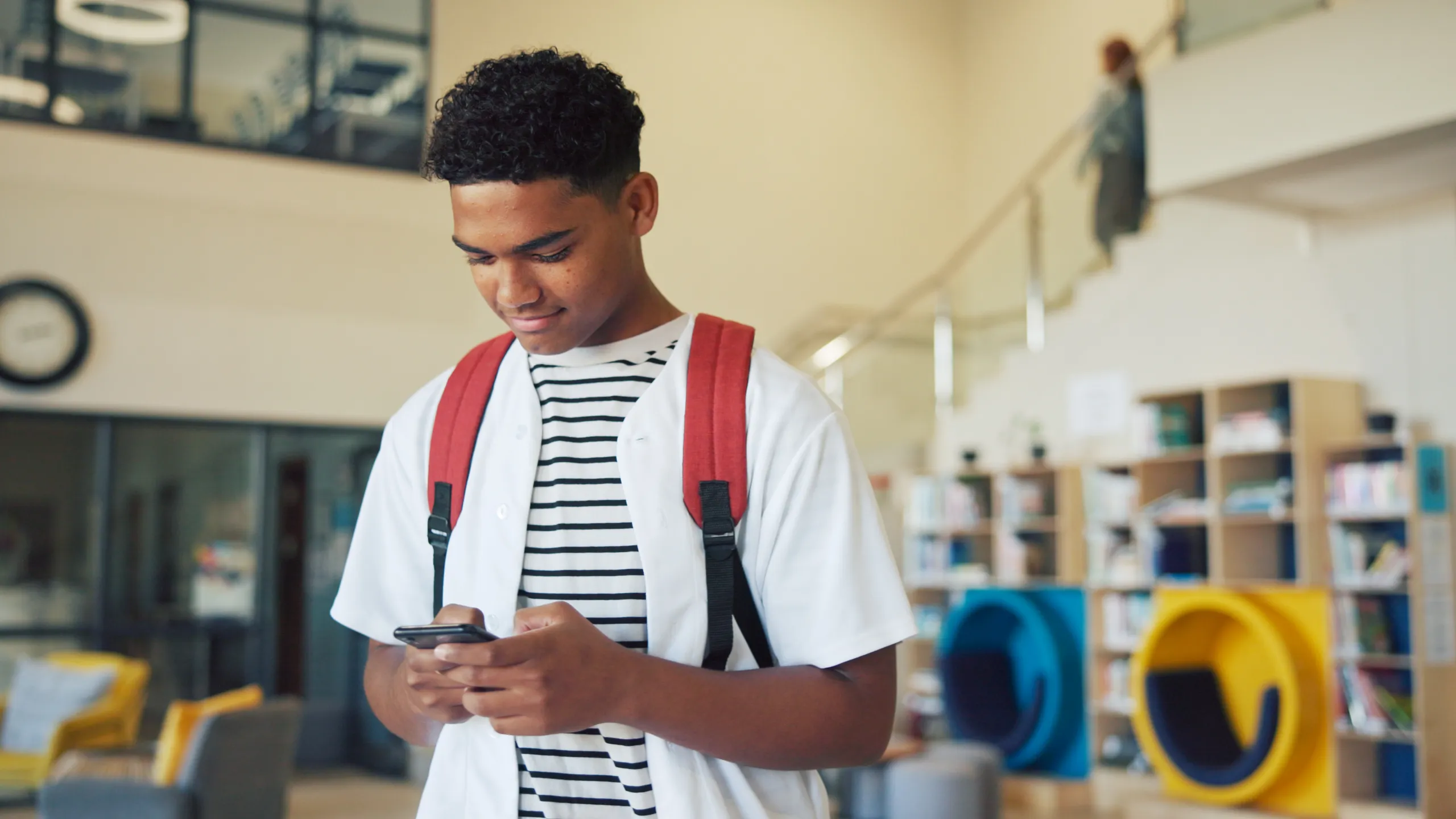 Education, phone and typing with boy student on high school campus for communication or study. App, learning and text message with teen learner in corridor for classroom schedule or timetable