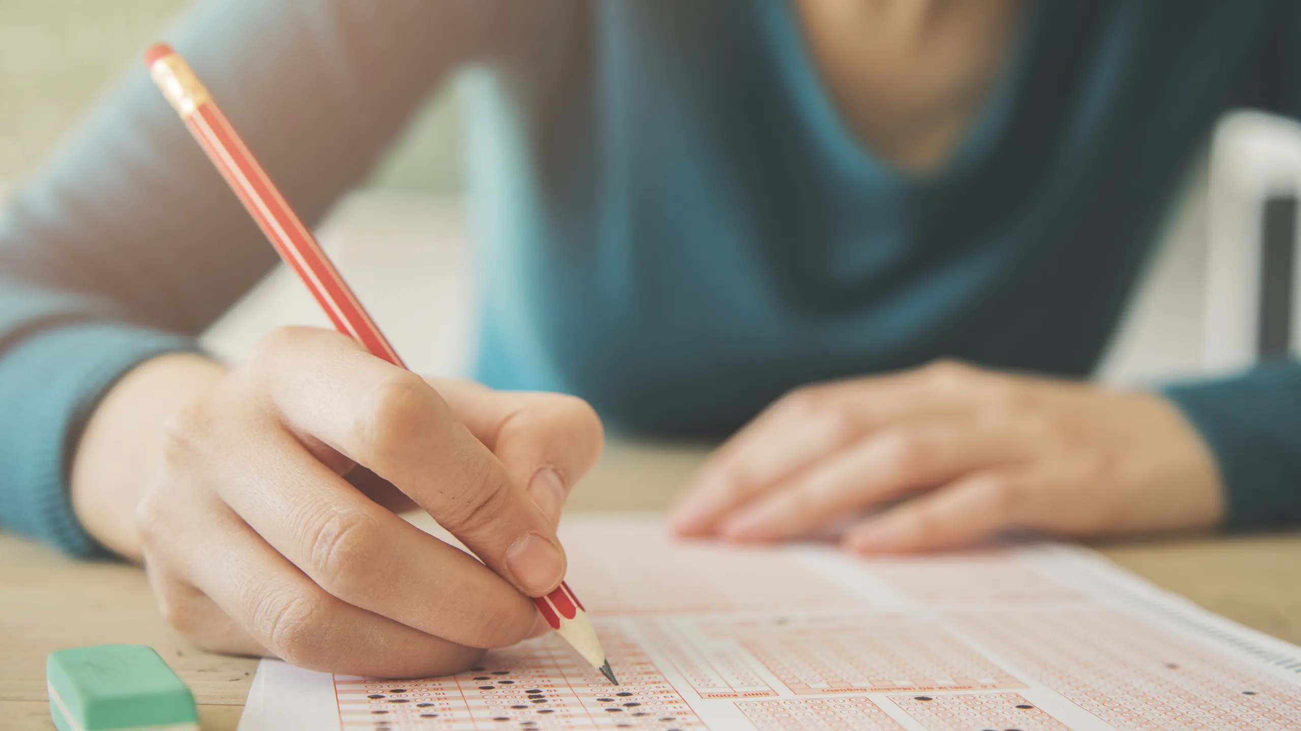 Female student holding pencil and examination paper