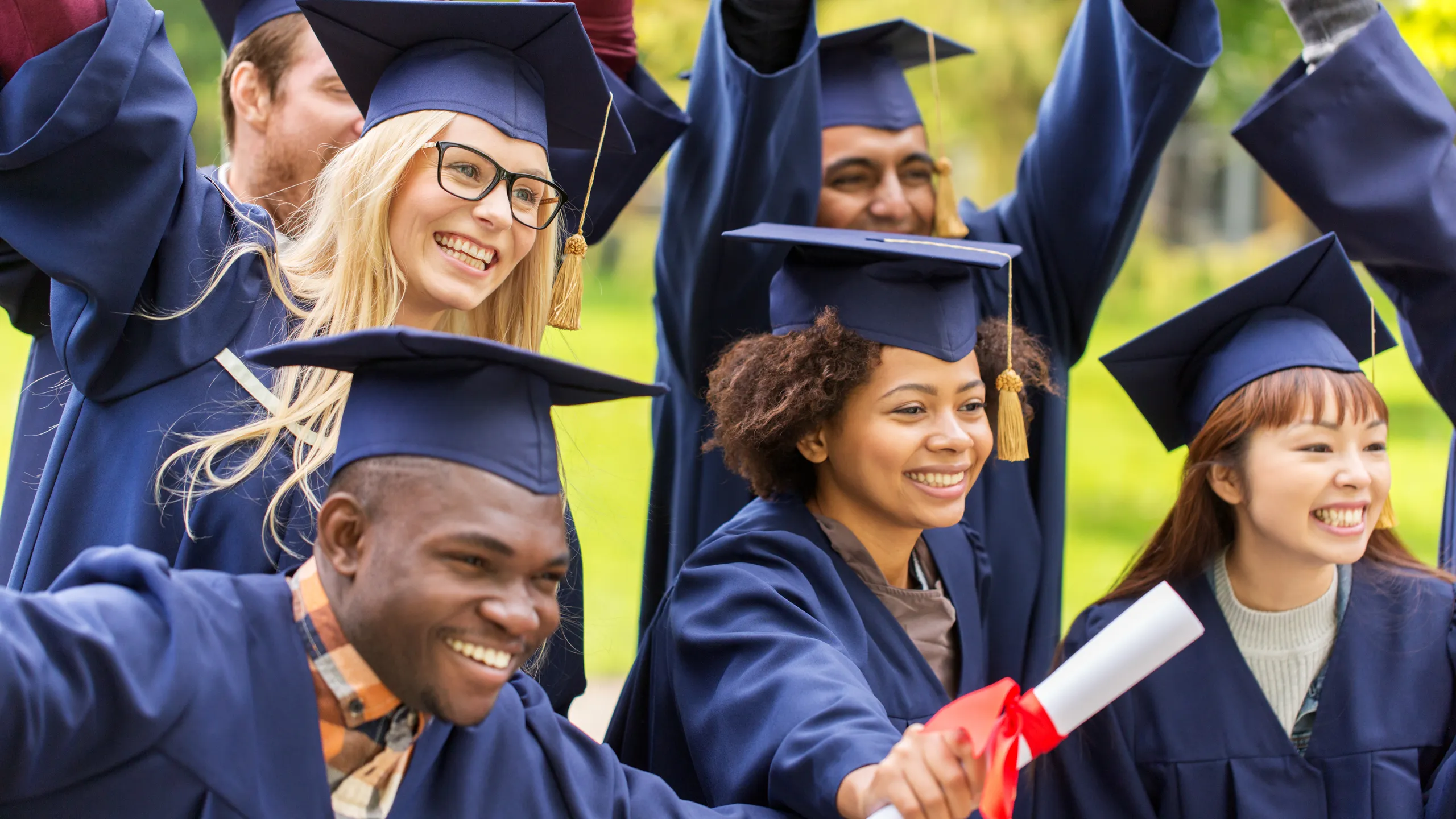 happy students in mortar boards with diplomas
