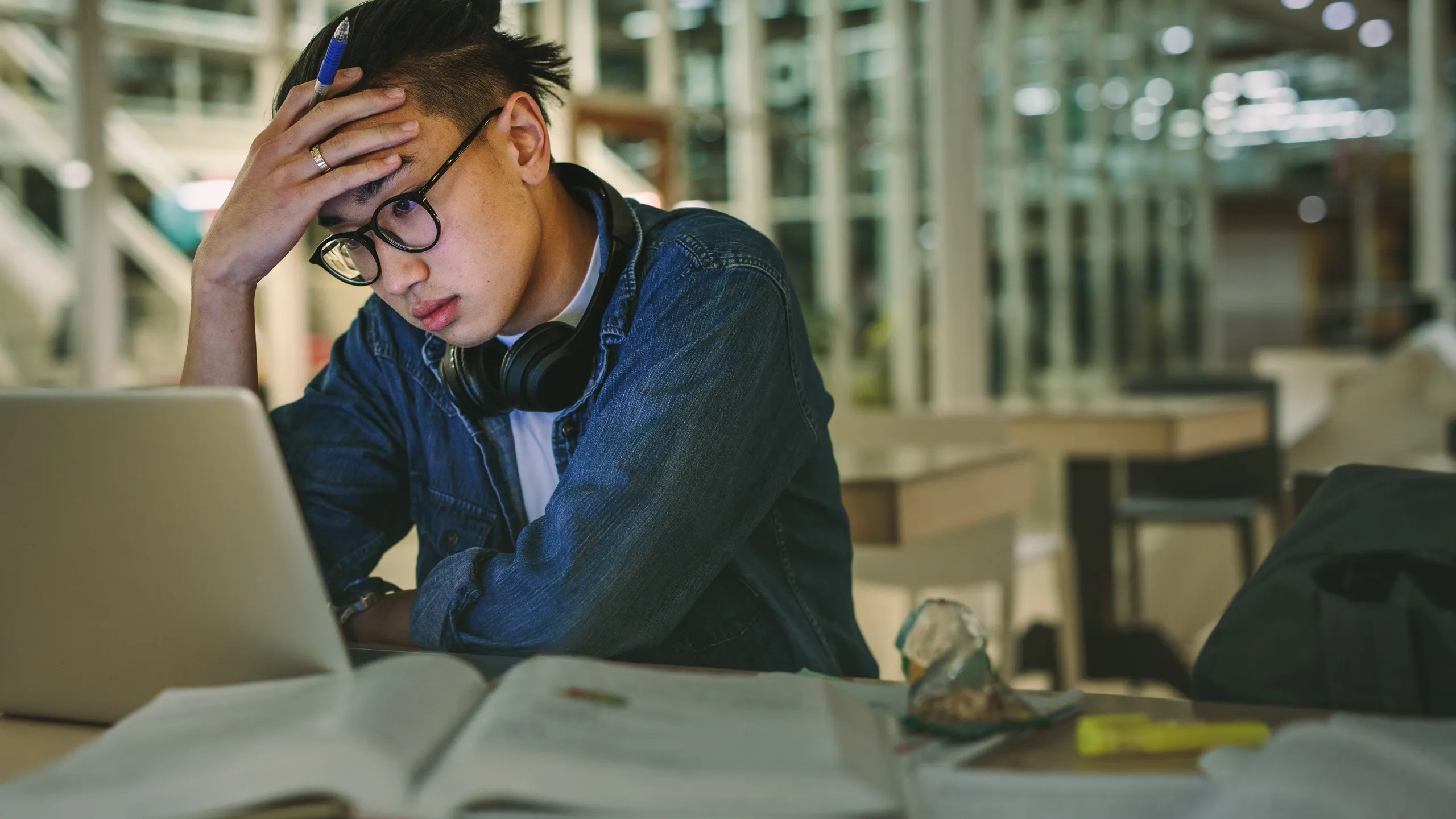 Depressed student sitting in library with laptop in college