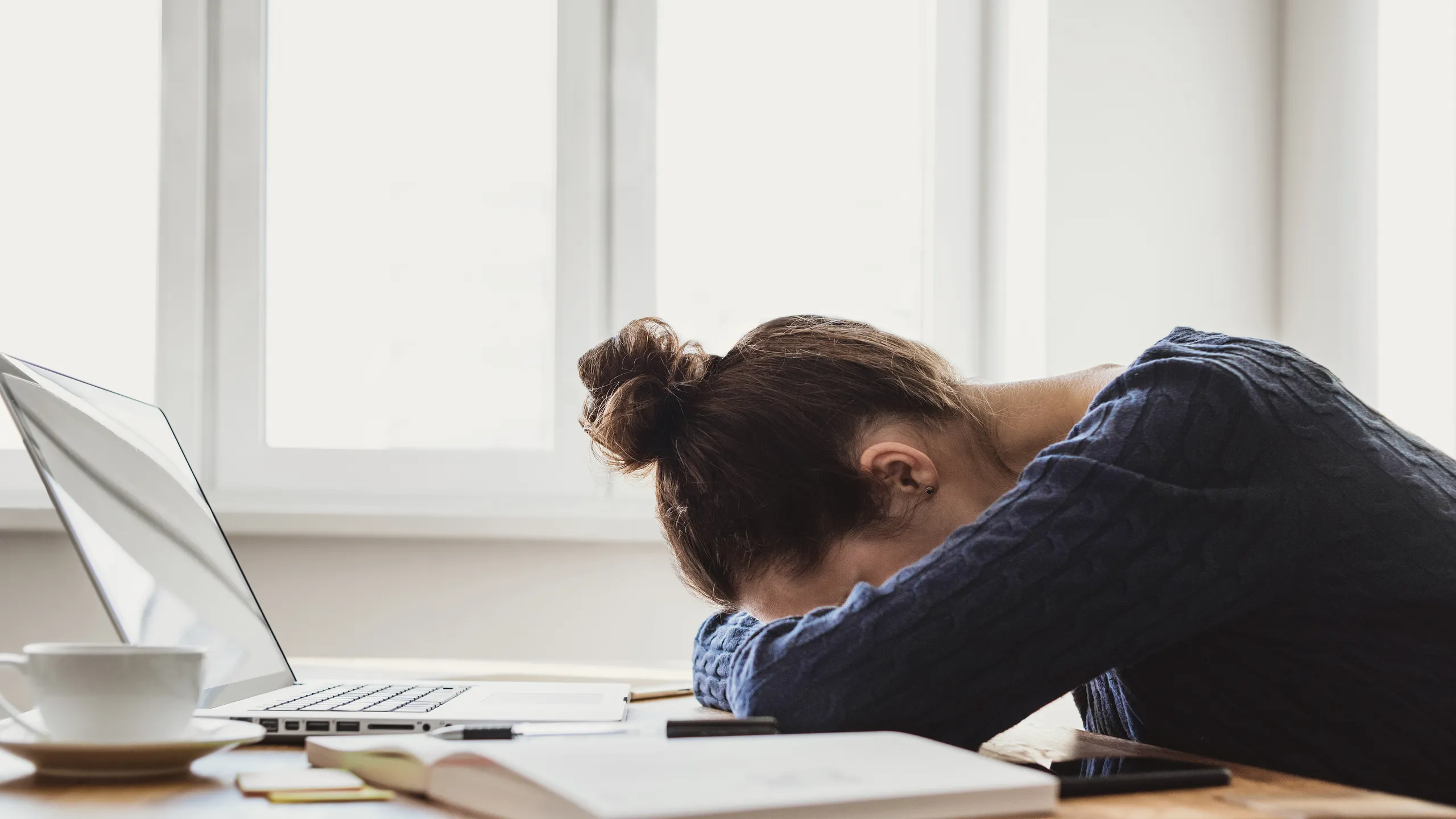 Tired and overworked business woman. Young exhausted girl sleeping on table during her work using laptop, digital tablet and smartphone. Entrepreneur, freelance worker or student in stress concept
