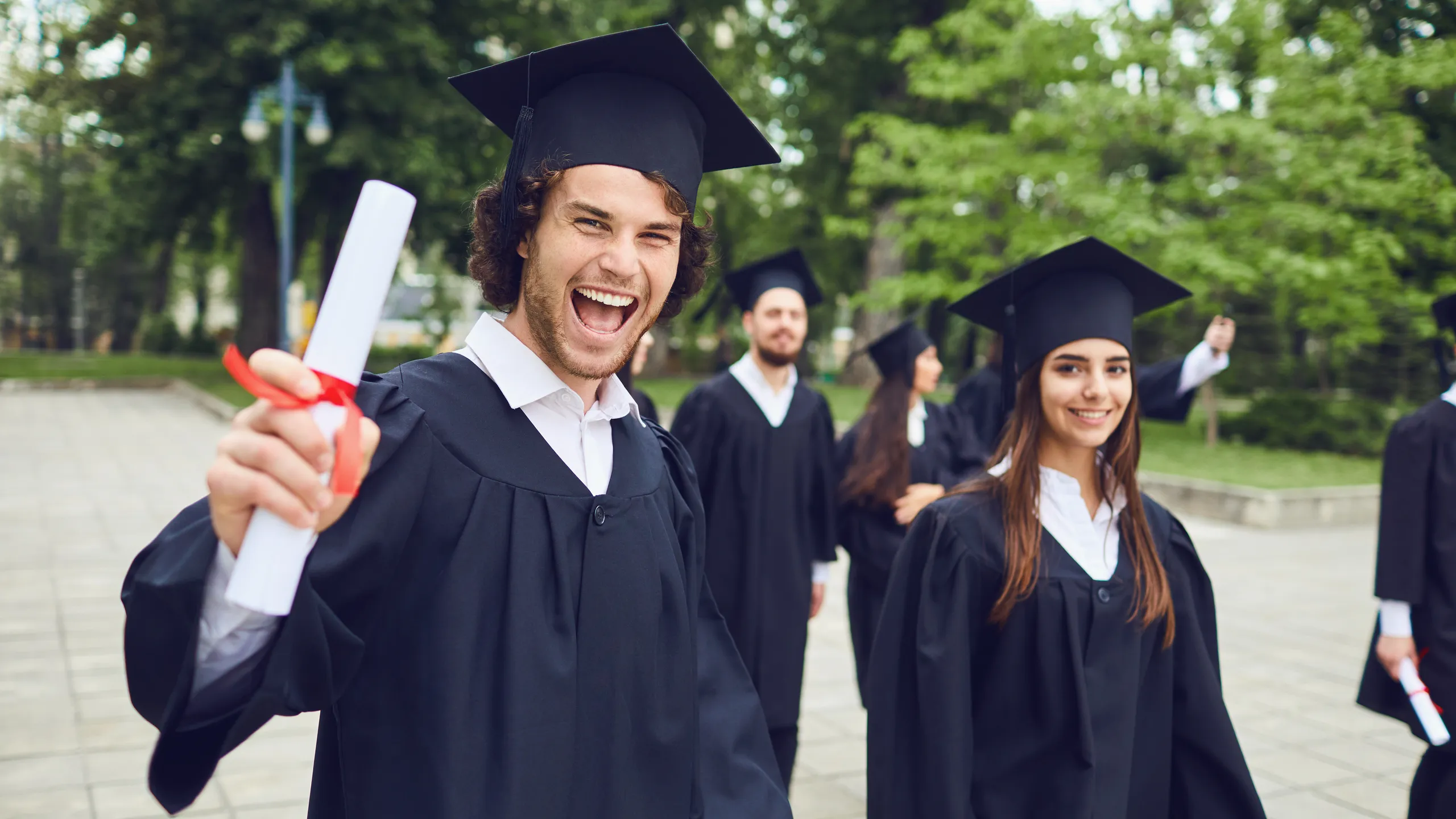 Man graduate is smiling against the background of university graduates.
