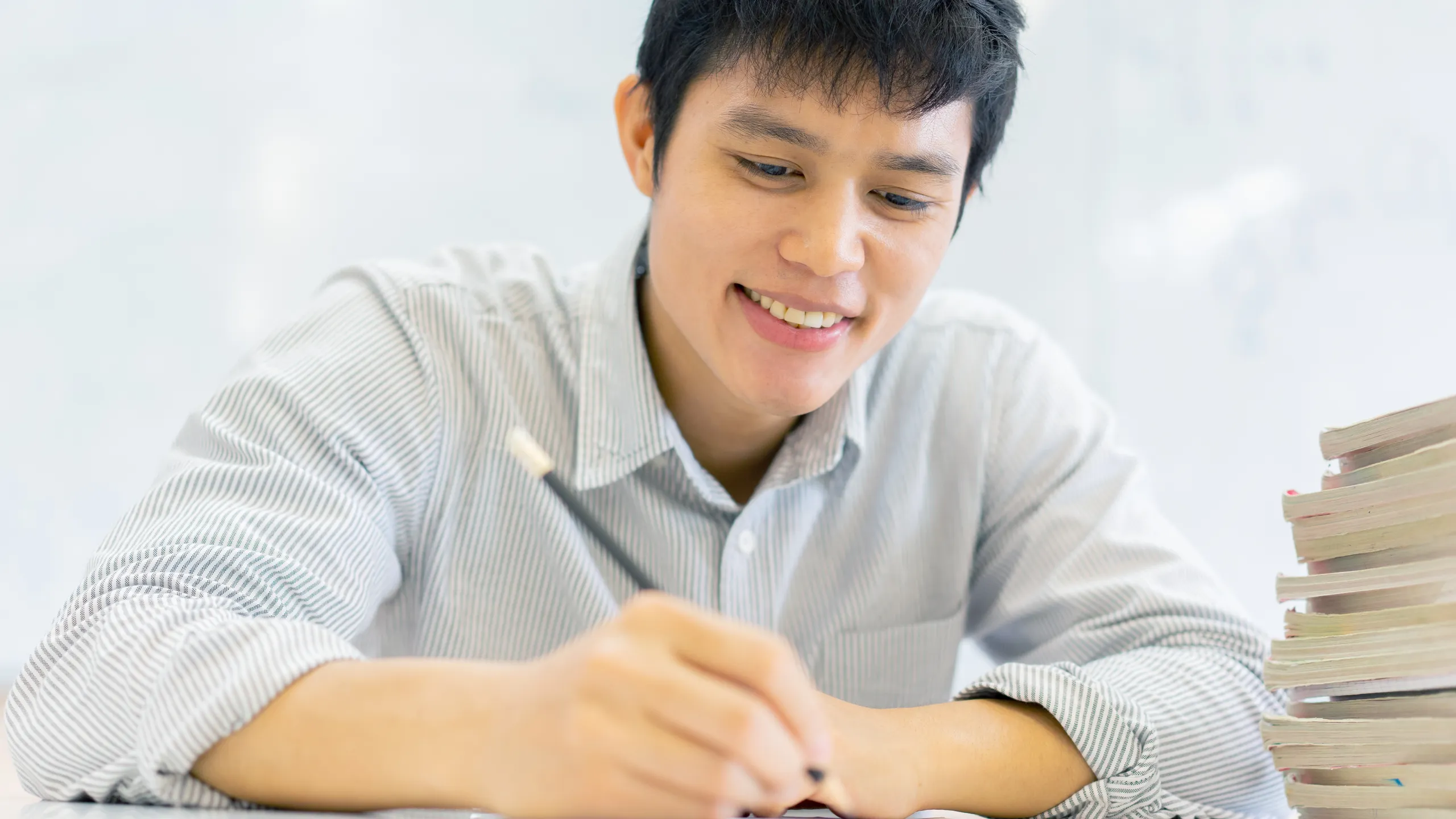 close up high school student man hand writing by mark choices on answer sheet paper for final examination test in classroom concept