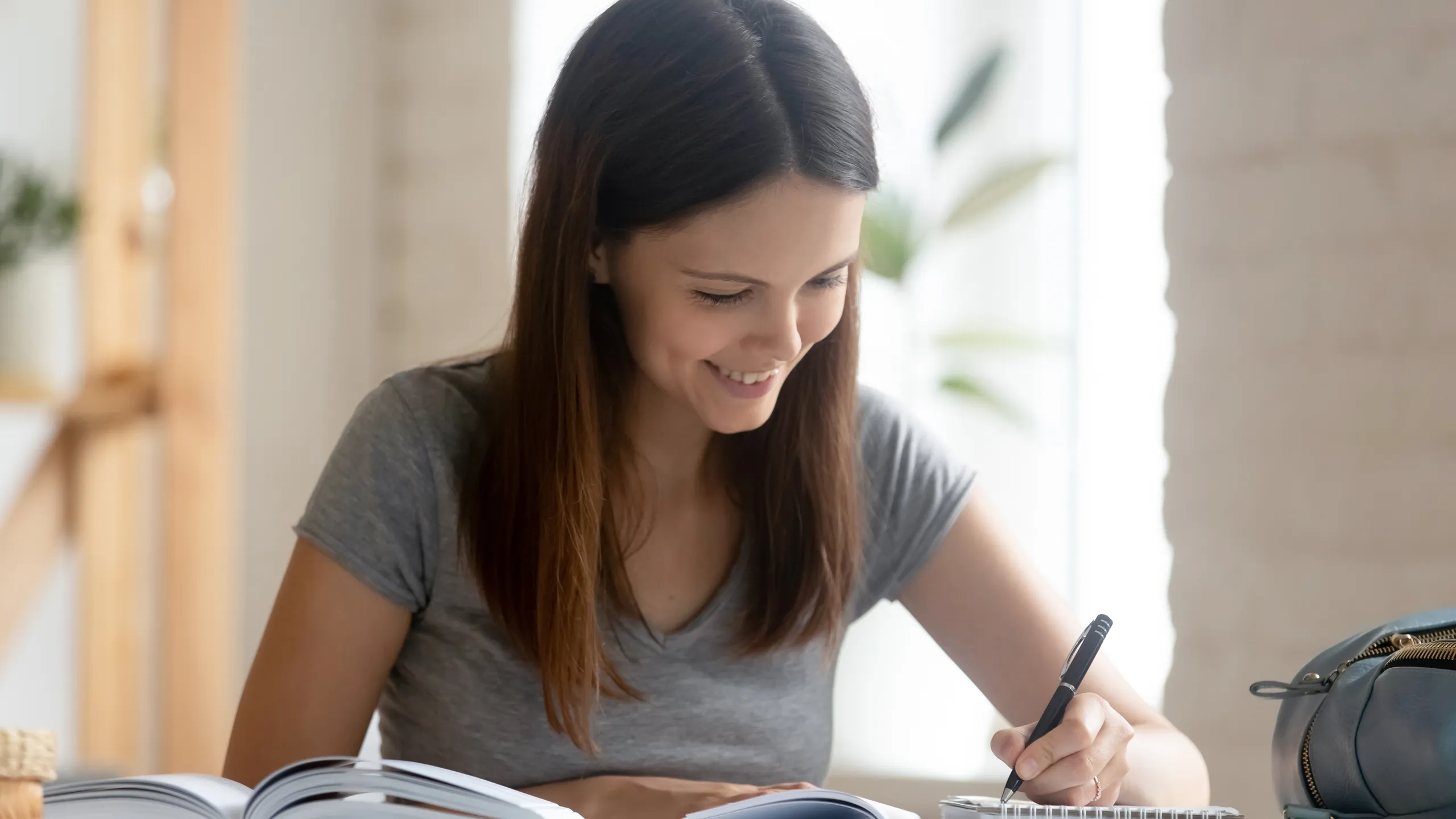 Student girl studying with handbook do homework seated at desk