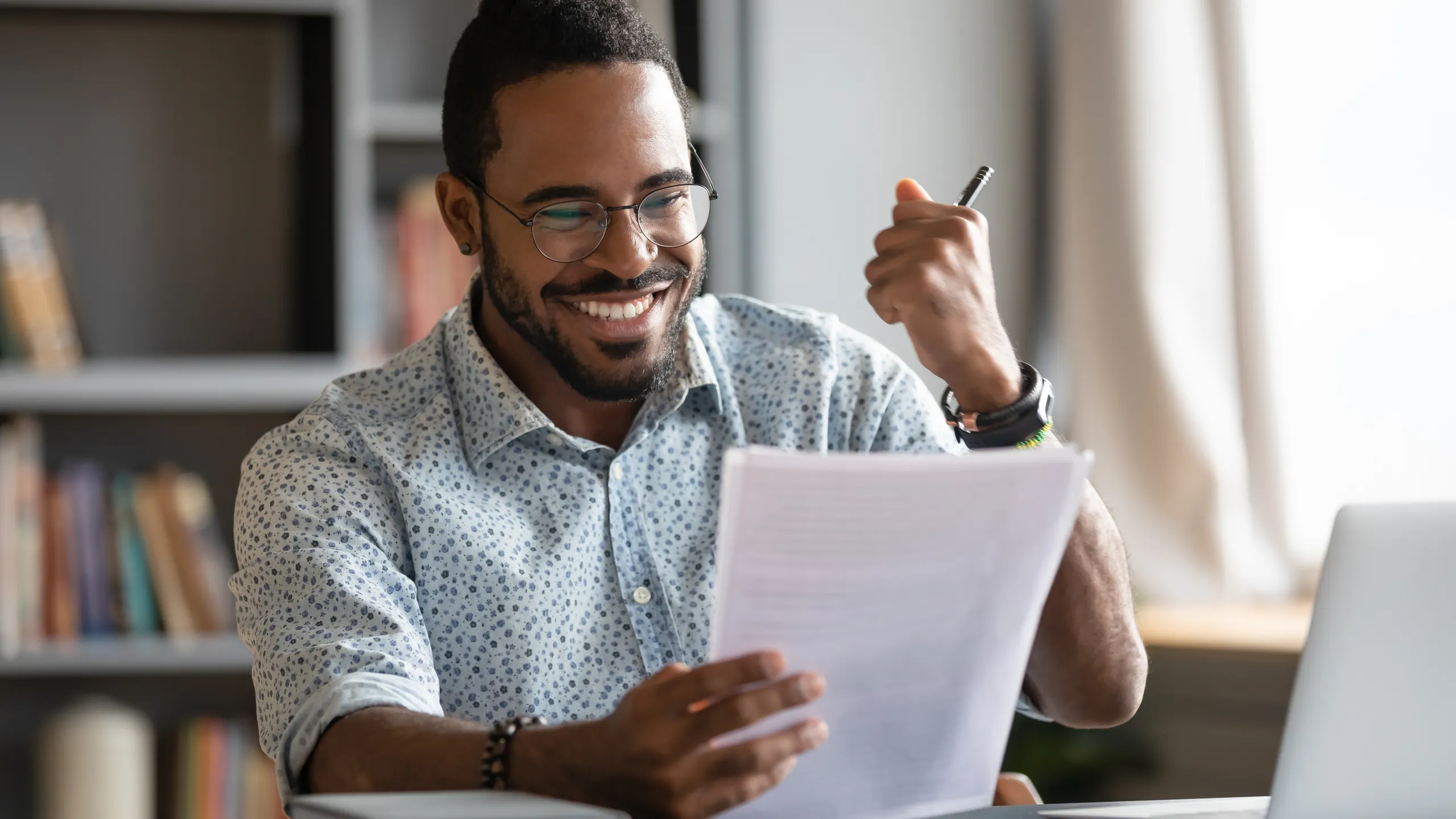 Happy satisfied african male professional read good news in document