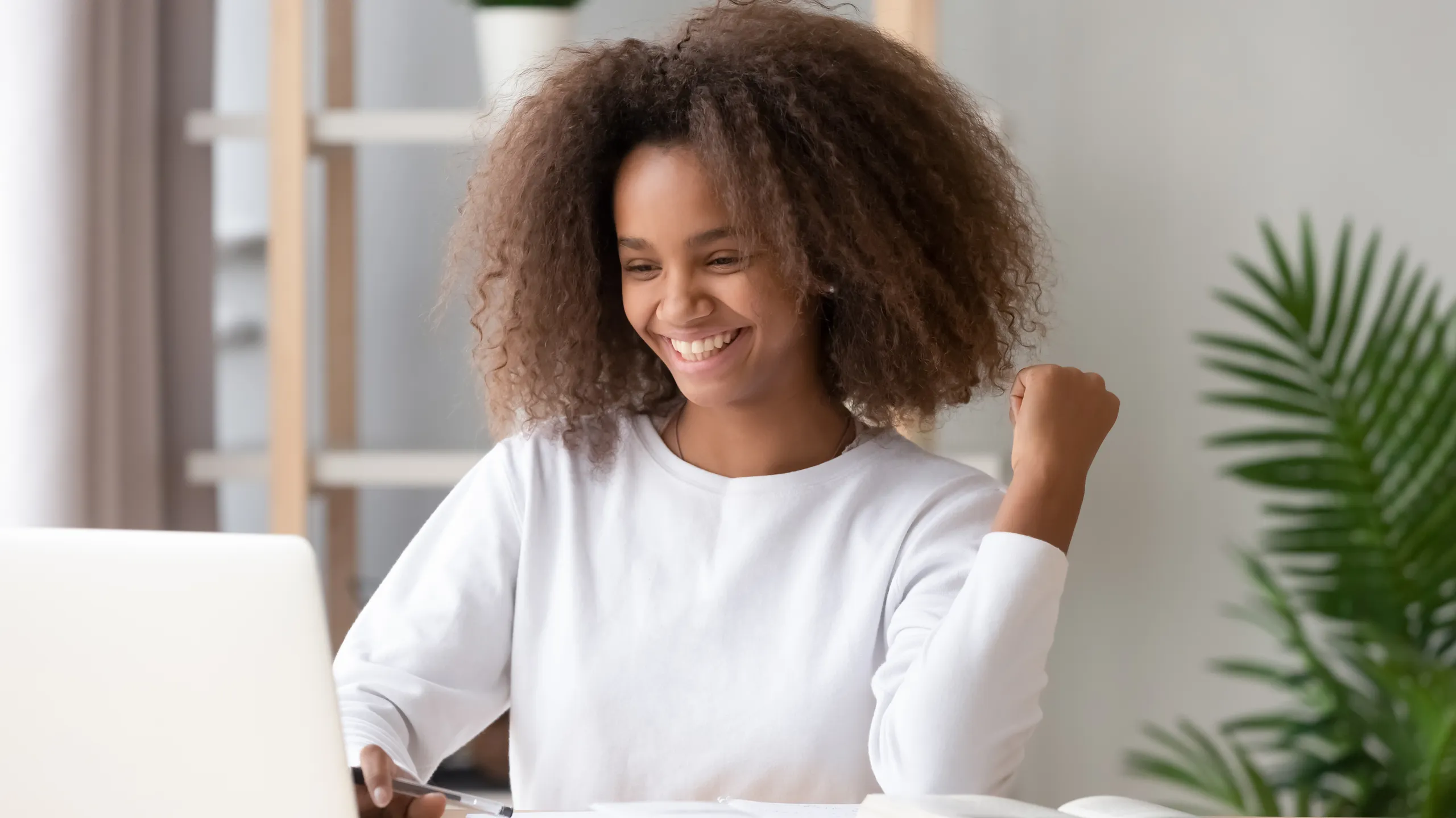 Excited overjoyed african teen girl student winner looking at laptop