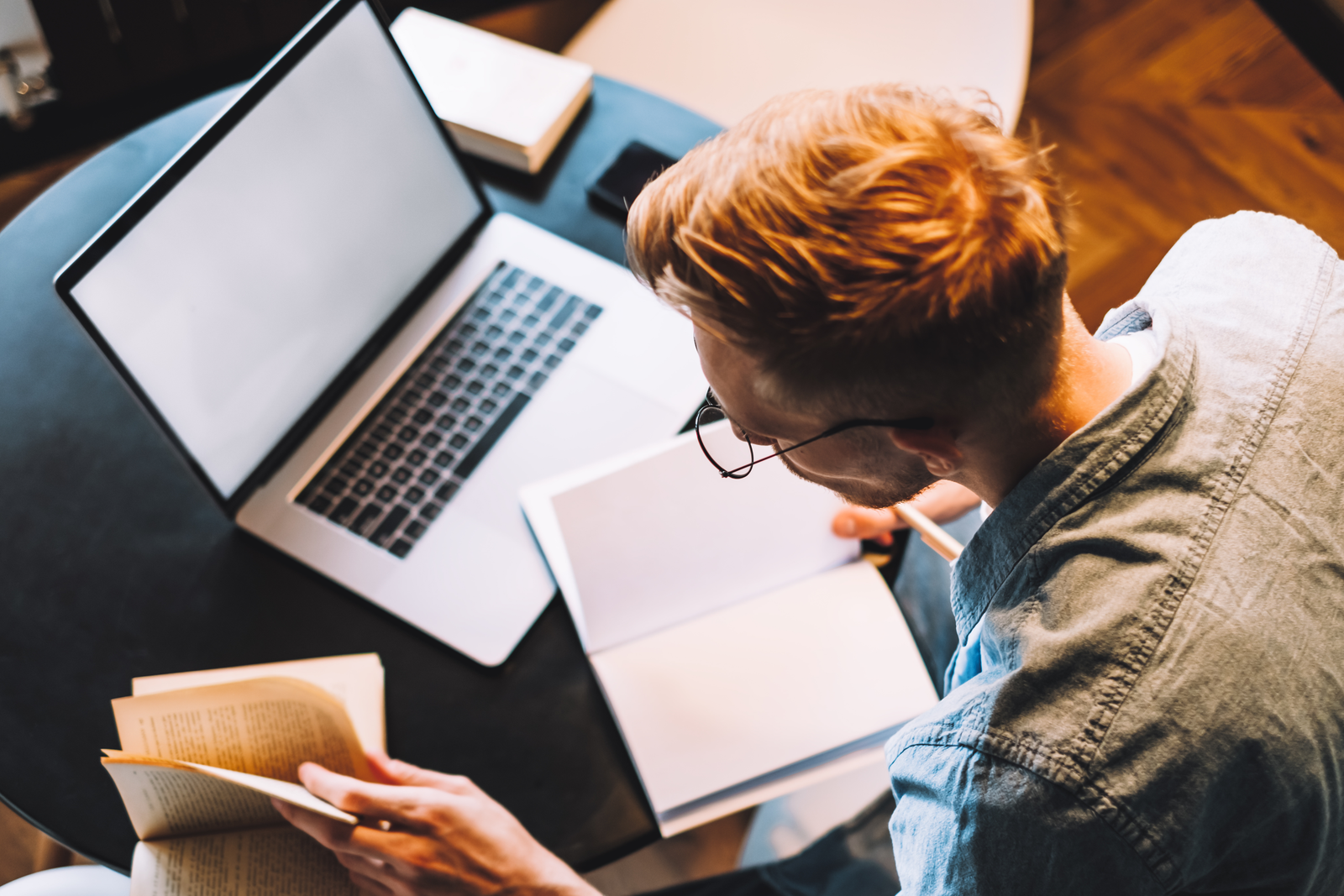 Focused caucasian man college student in glasses studying with b