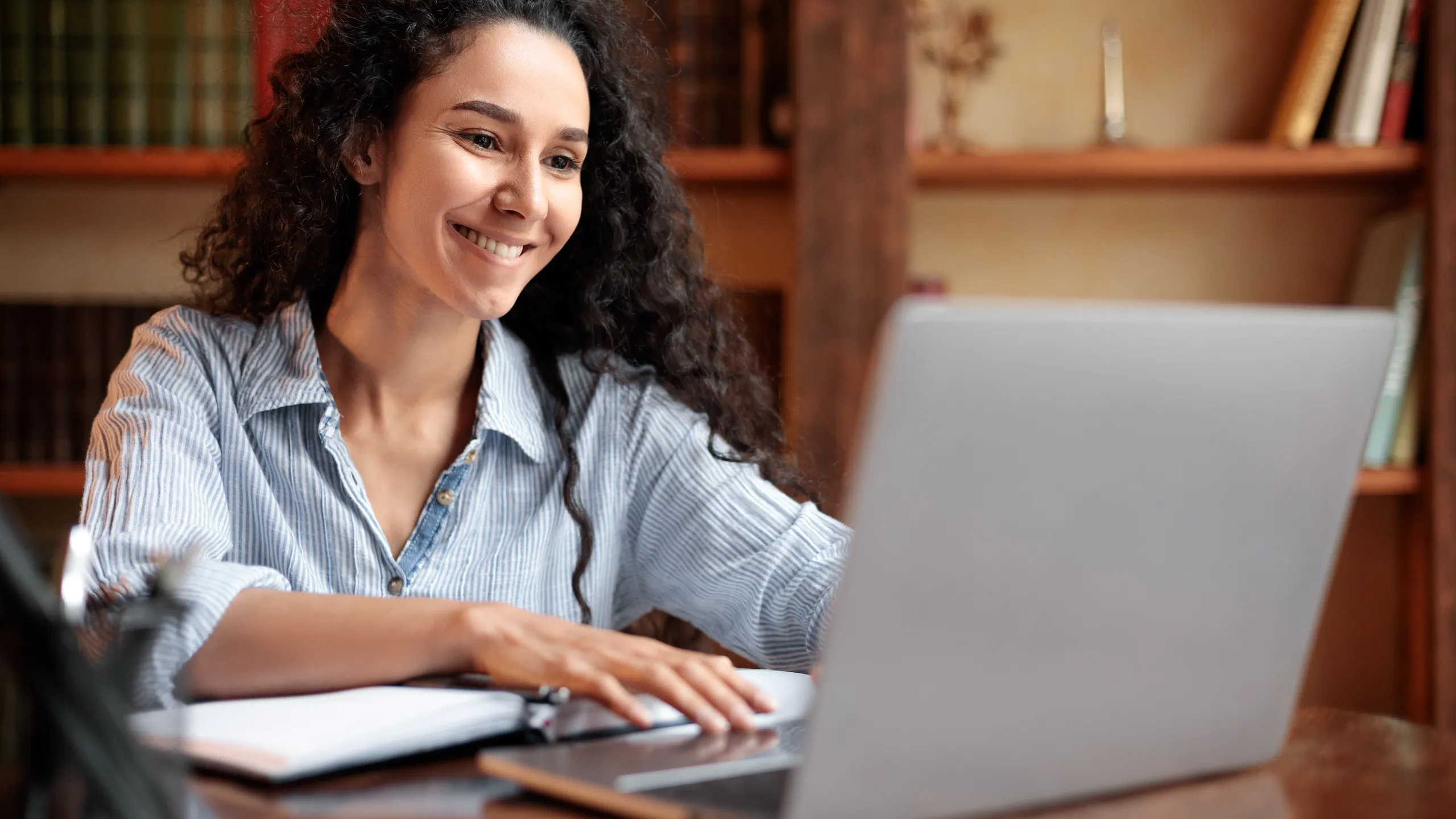 Woman sitting at desk, using computer and typing on keyboard