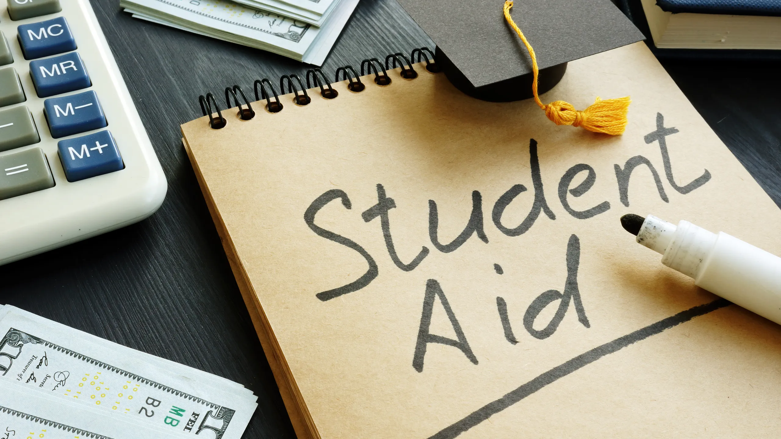 Student aid sign with small graduation cap and money.