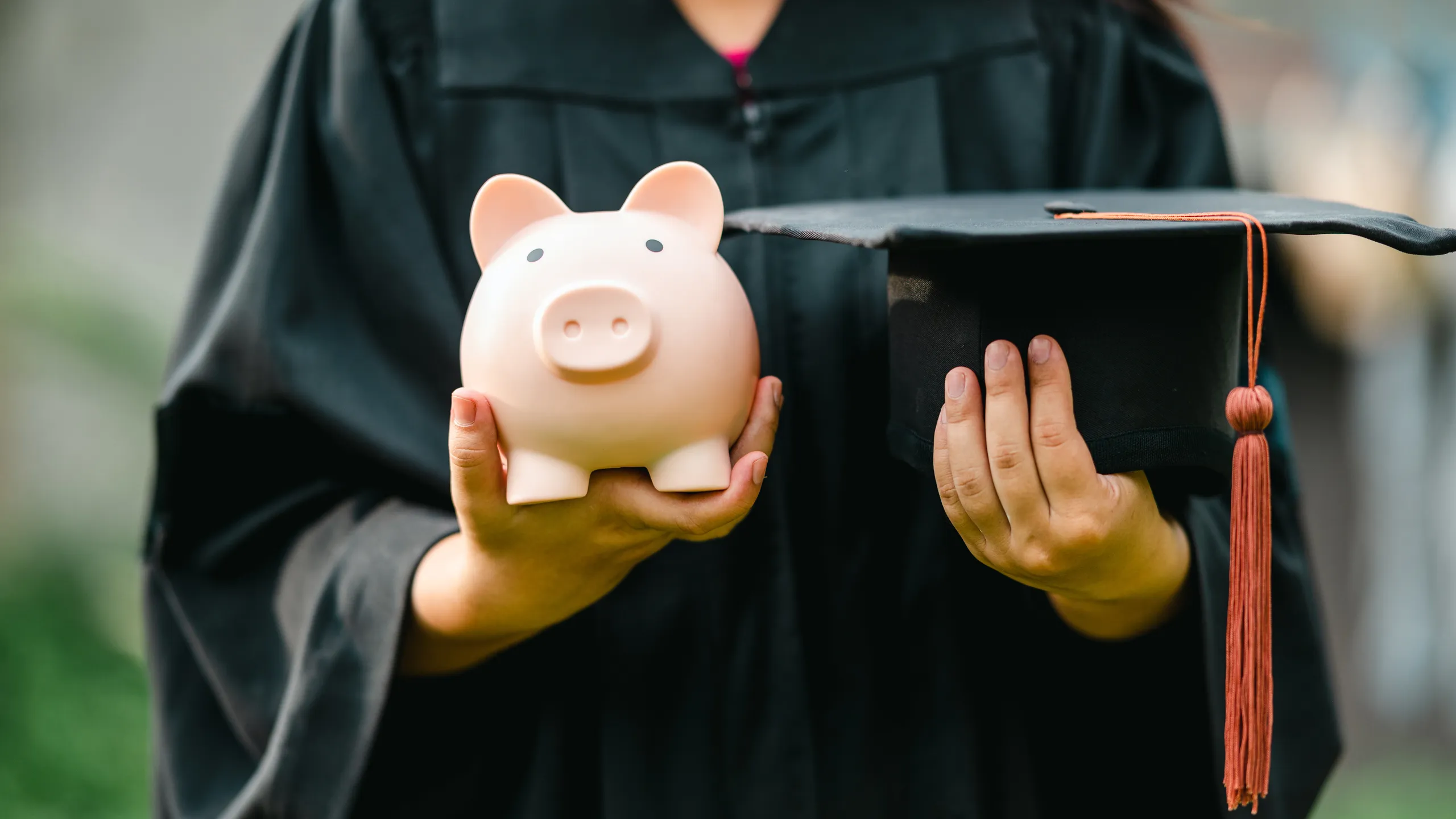 graduates holding piggy banks saving concept