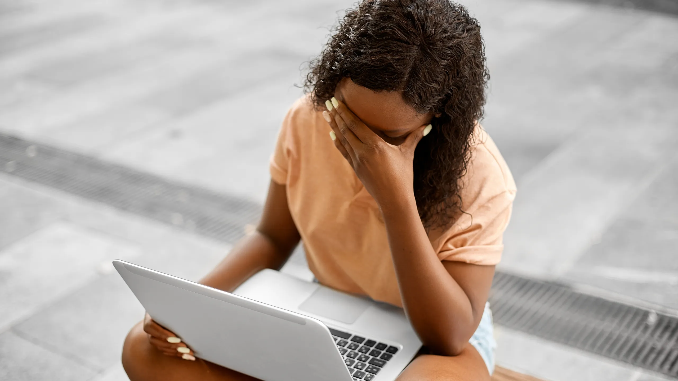 stressed african student girl with laptop in city
