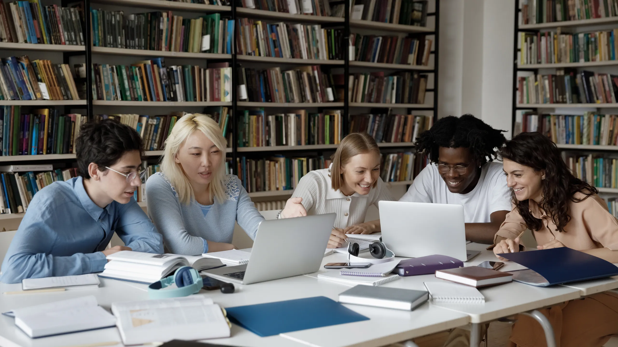 Group of multiethnic students studying together in library using laptop