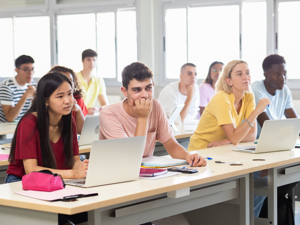 Group of multi-ethnic teenage student listening to the lesson in class in a classroom with computers. Education and technology, back to school