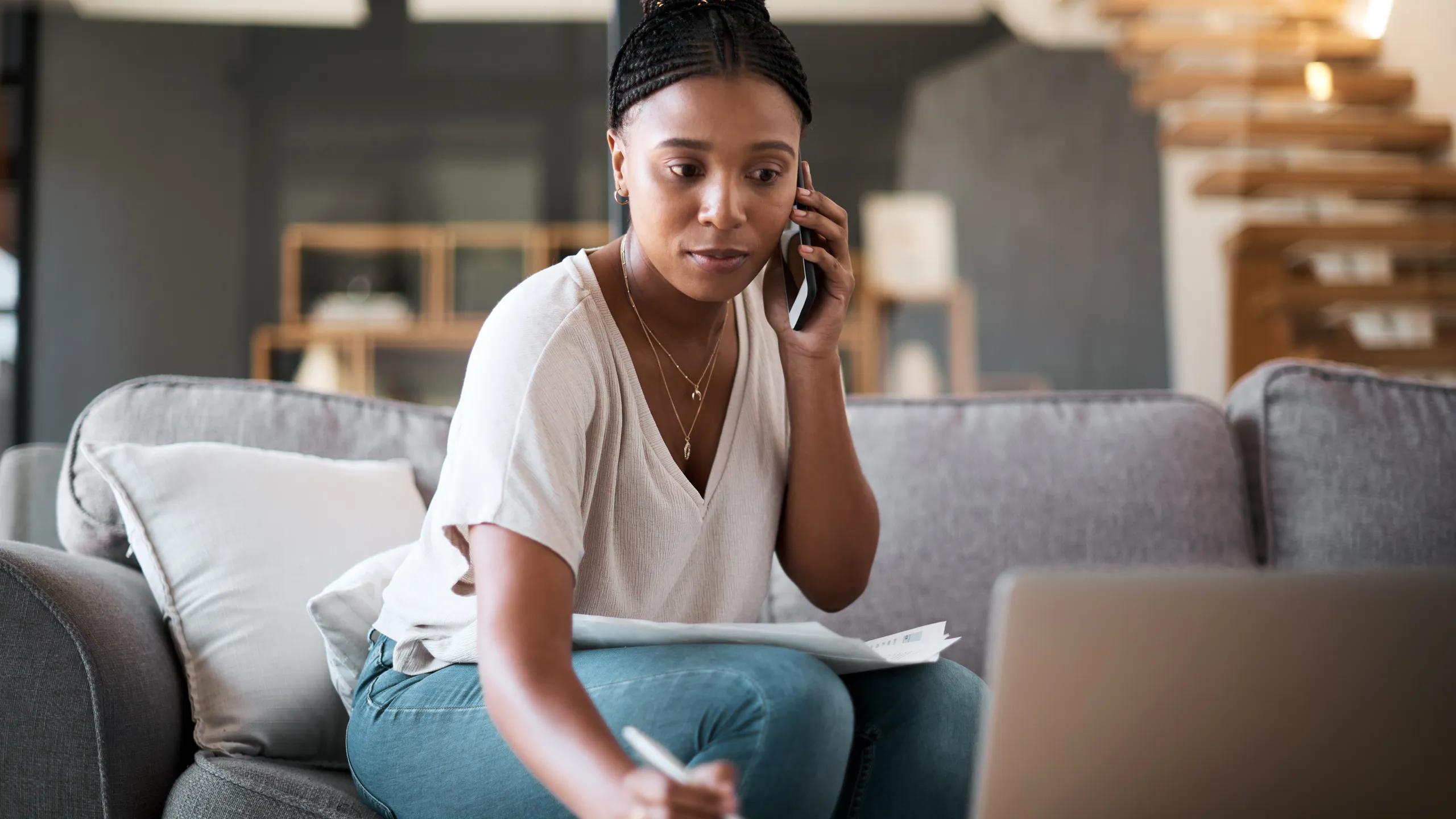 Woman, call and laptop budget planning conversation with online financial consultant to help with taxes on living room sofa. Black woman, work from home and remote internet fintech banking consulting