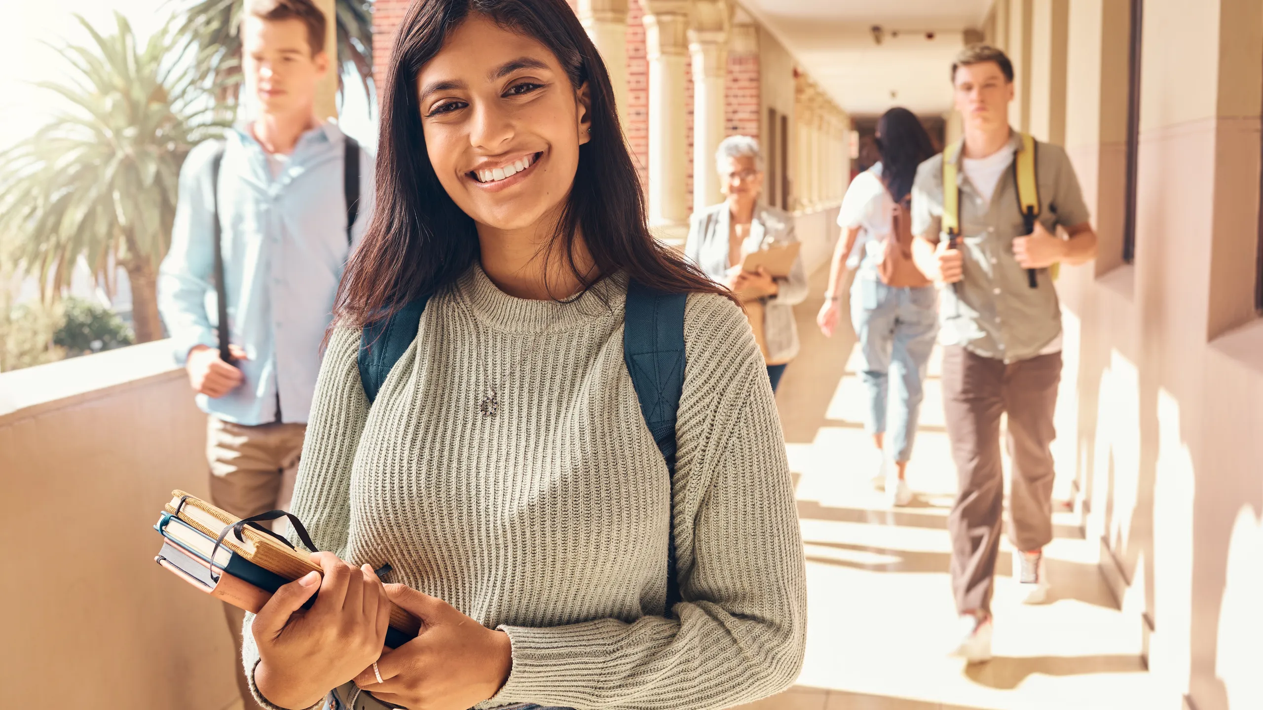 University student, indian woman and portrait at campus outdoor with books of learning, education or knowledge, scholarship and motivation. Happy, smile and young college student, studying or academy