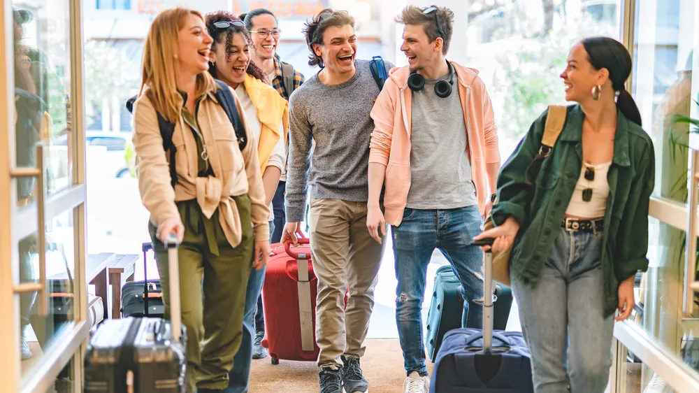 Group of university college tourist walking inside the hotel with suitcases -Young happy students enjoying summer holiday-Tourism Vacation and Lifestyle concept with people-Youth culture-Spring time