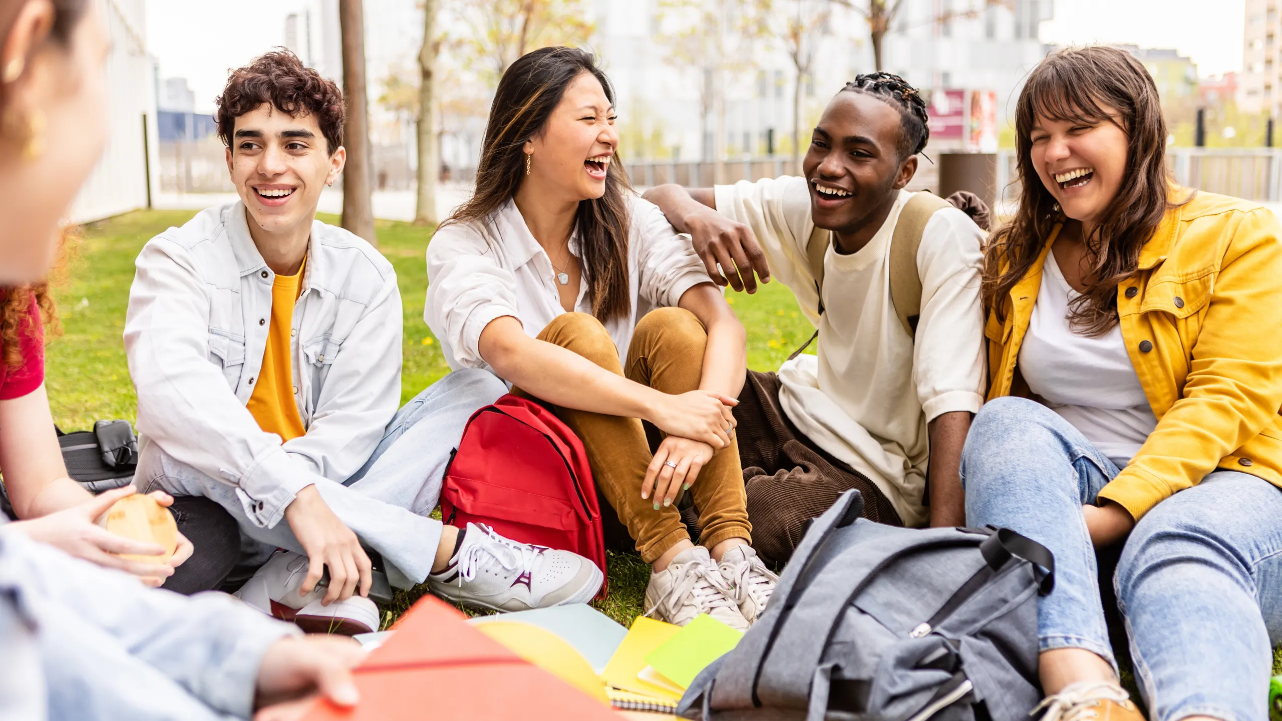 Young group of multiracial students sitting on the grass at university campus