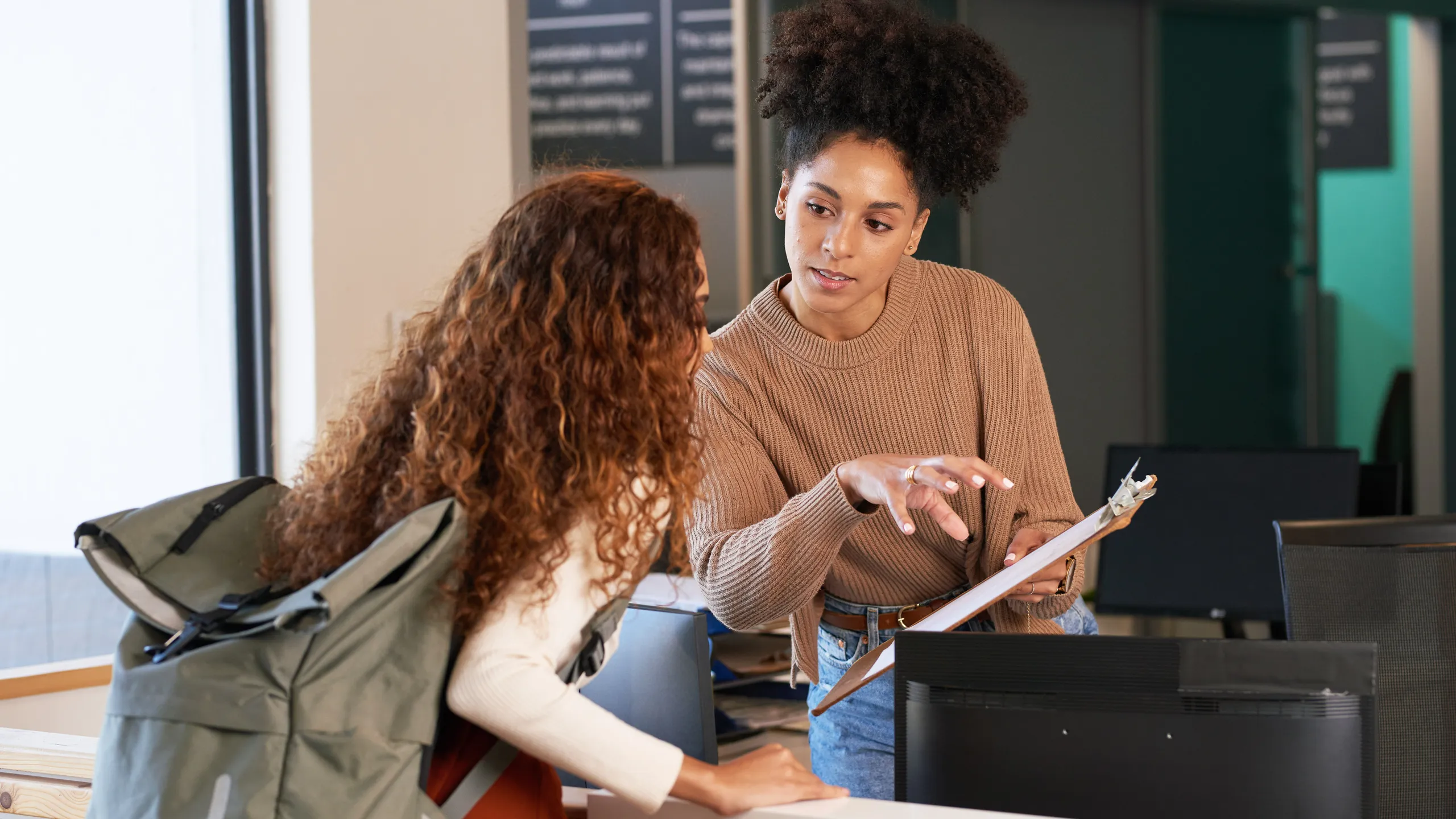 Young woman checks in at front desk, reception, hotel, college library admission