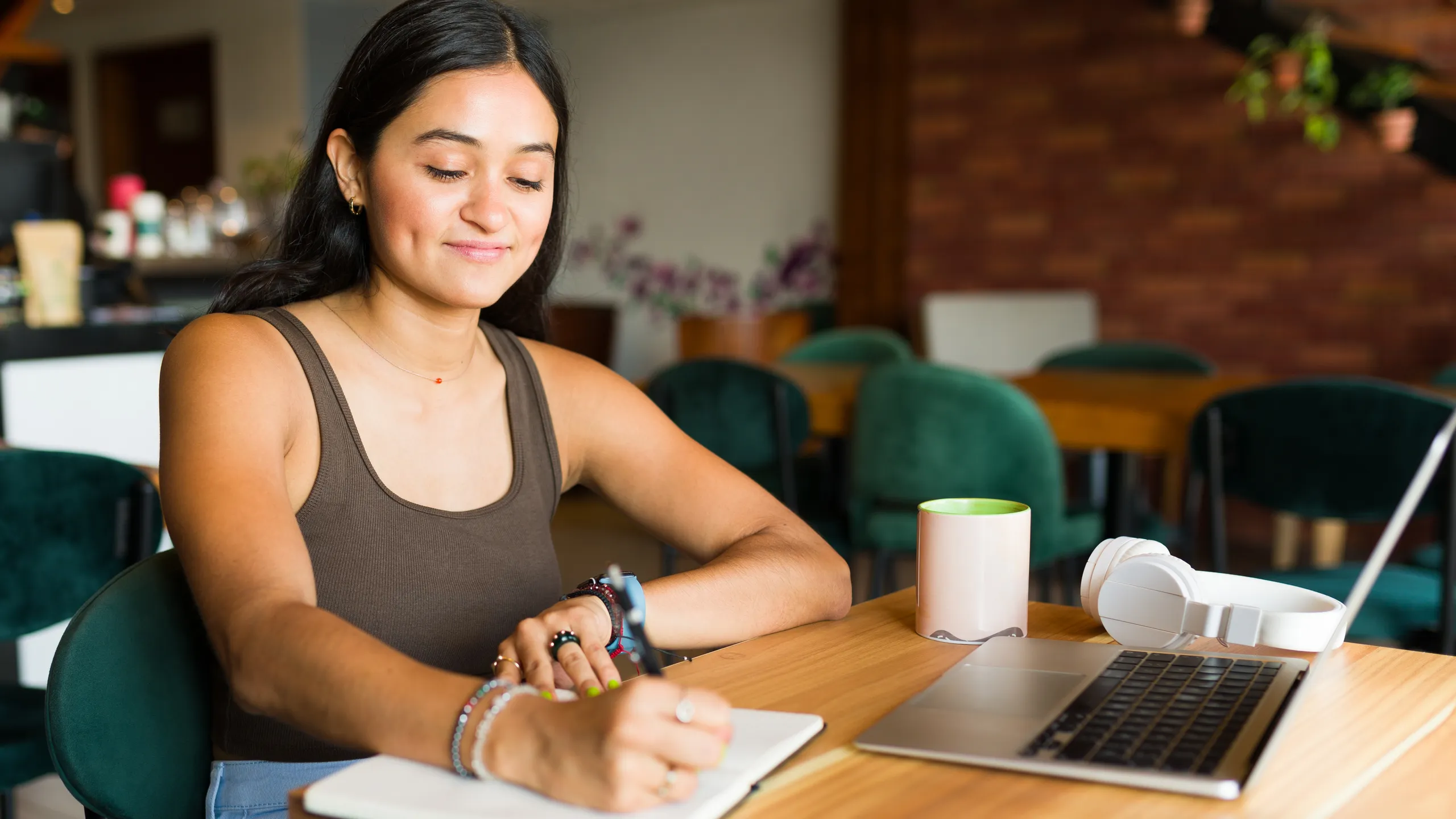 Happy young woman writing while doing freelance work