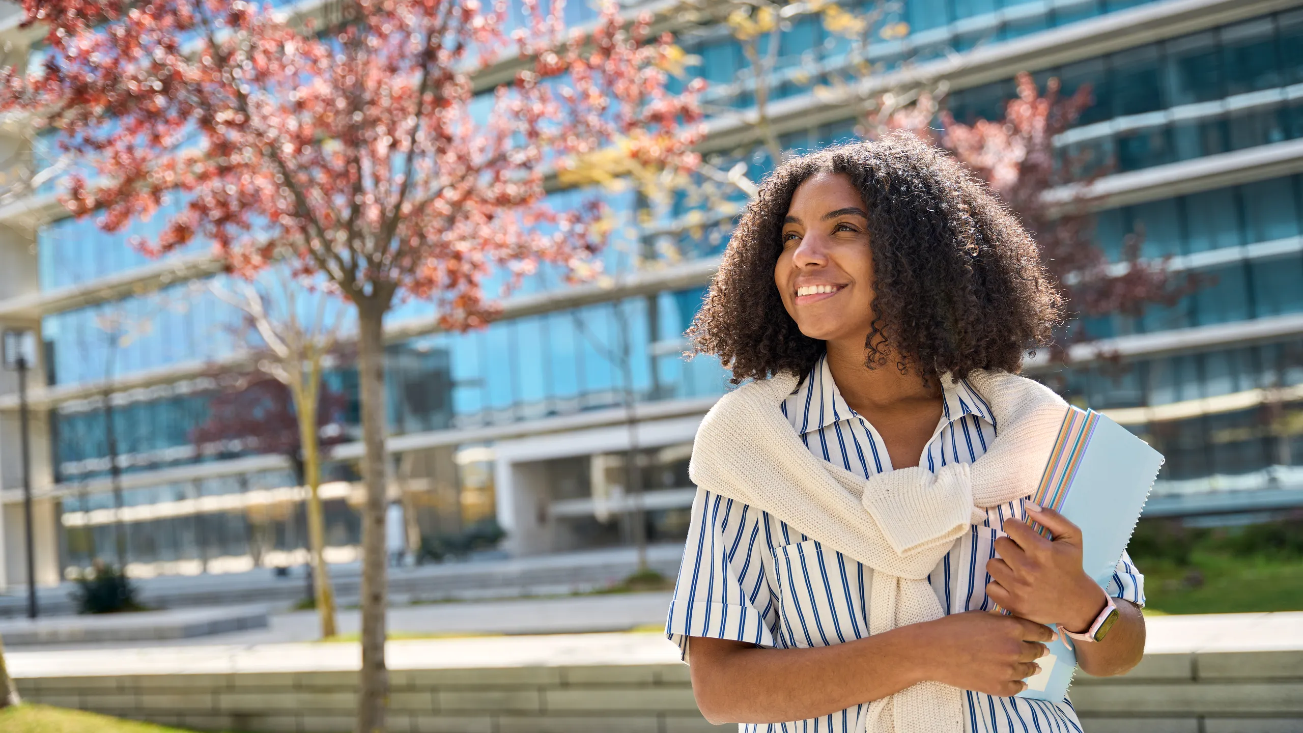 Happy African American girl student standing in university campus looking away.