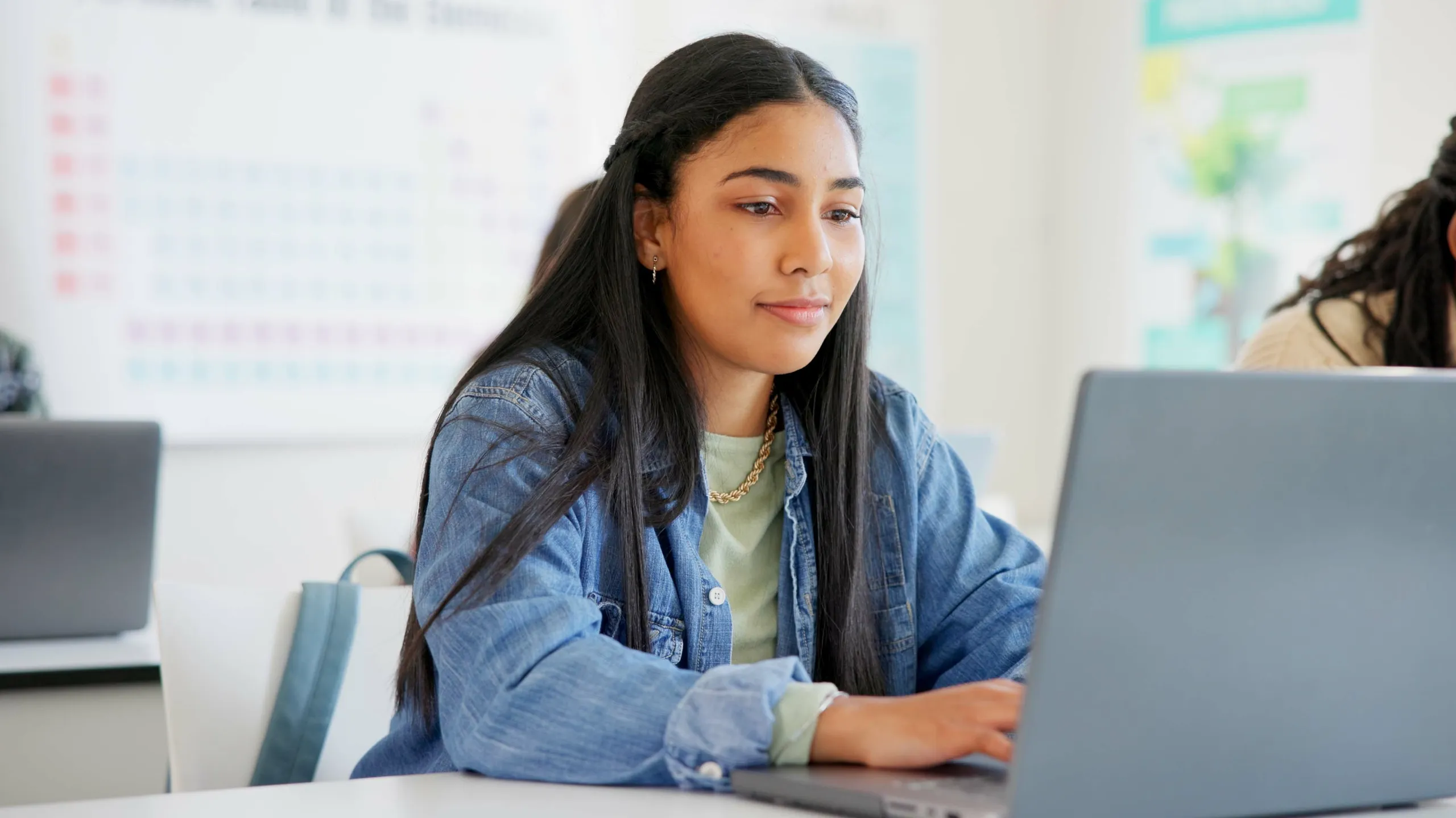 Woman, student and laptop for classroom education, e learning and studying or research in college. Young people typing on computer for university or school information, FAQ or scholarship application