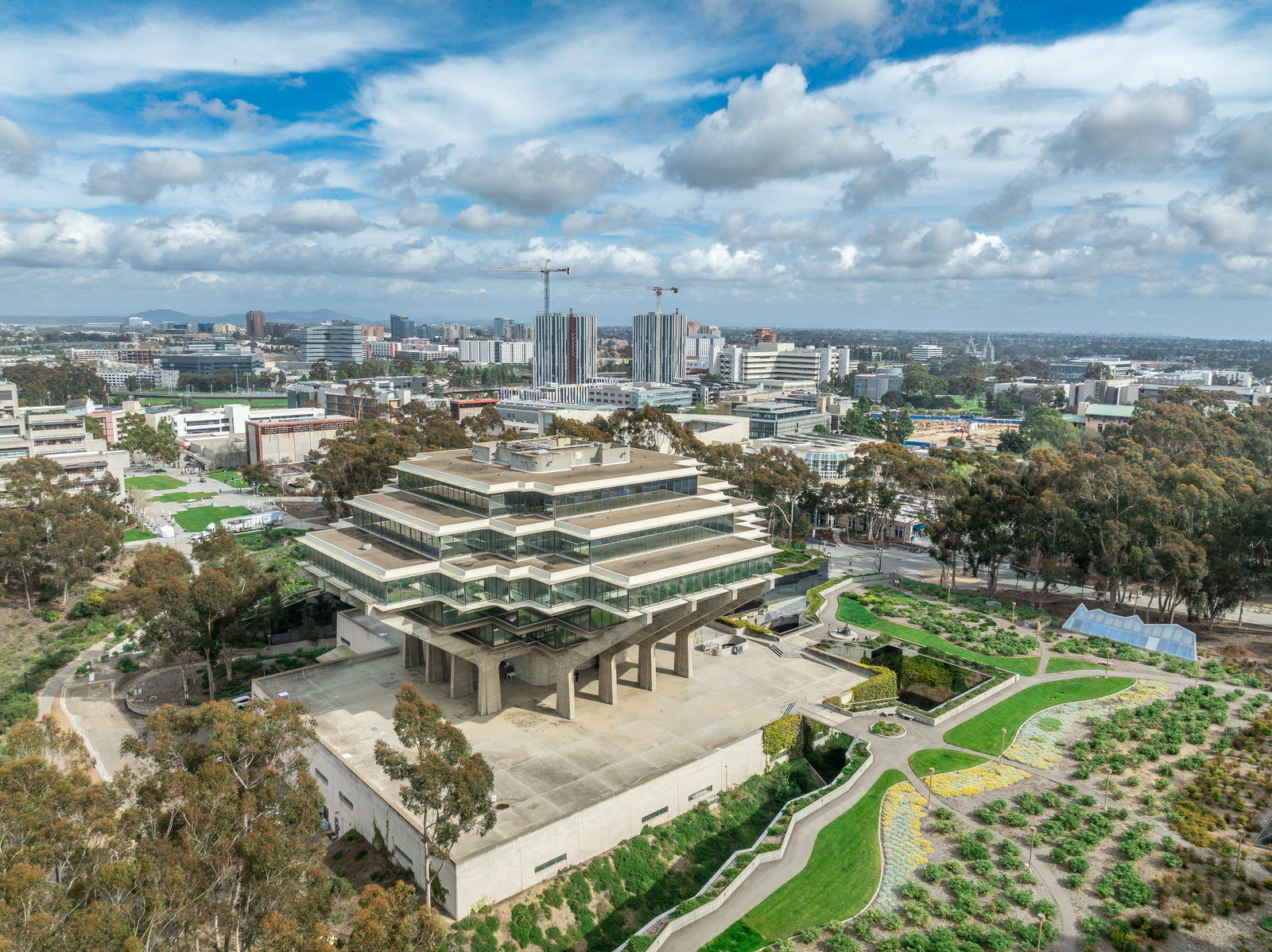 Aerial view of Geysel library at the University of California San Diego, futuristic building, columns holding up upper floor like books, next to the snake path