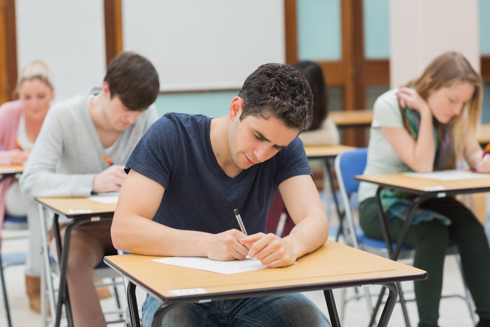 Students sitting in an exam hall doing an exam in university-1