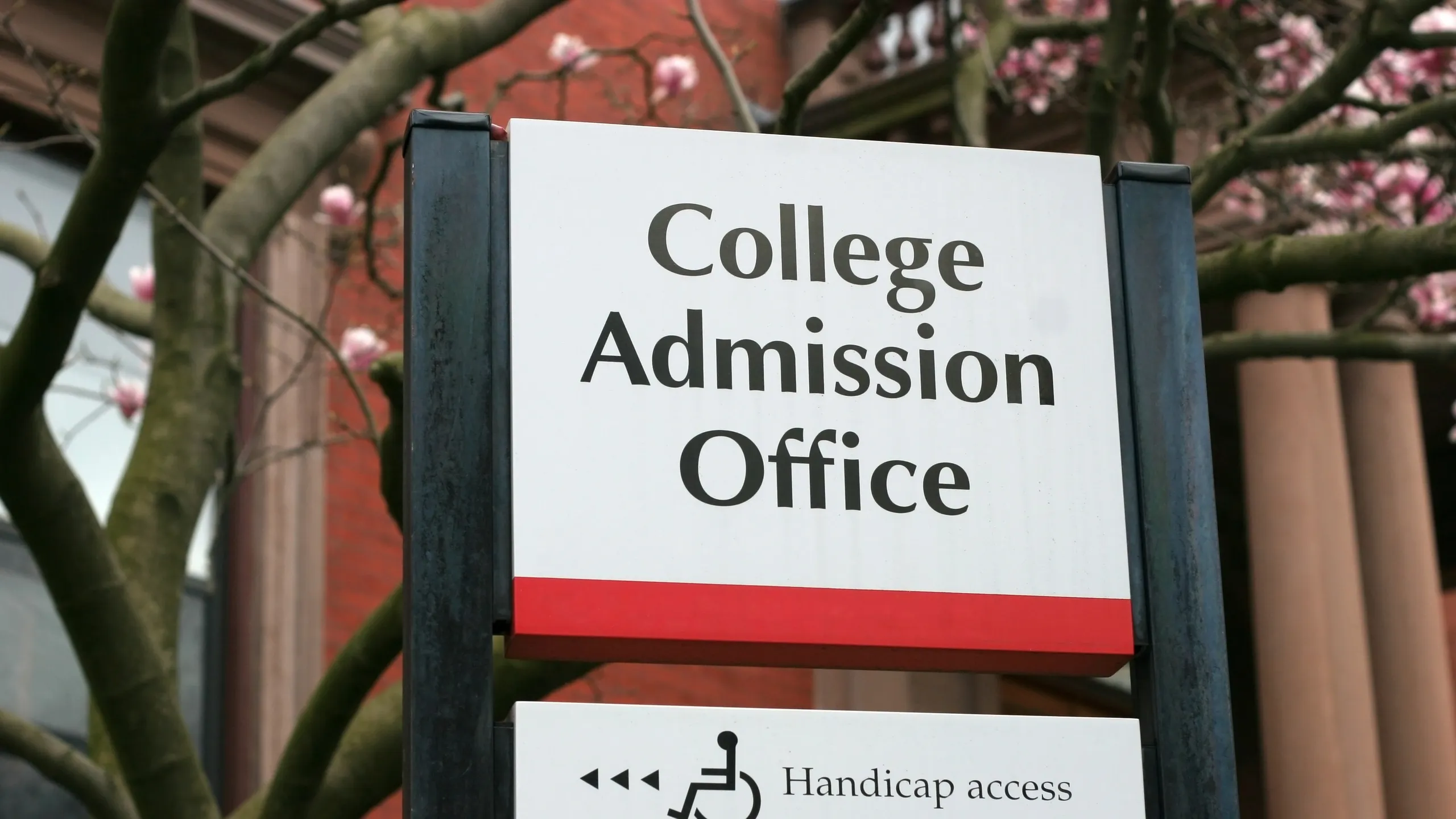 A building sign on a college campus stating "College Admission Office"
