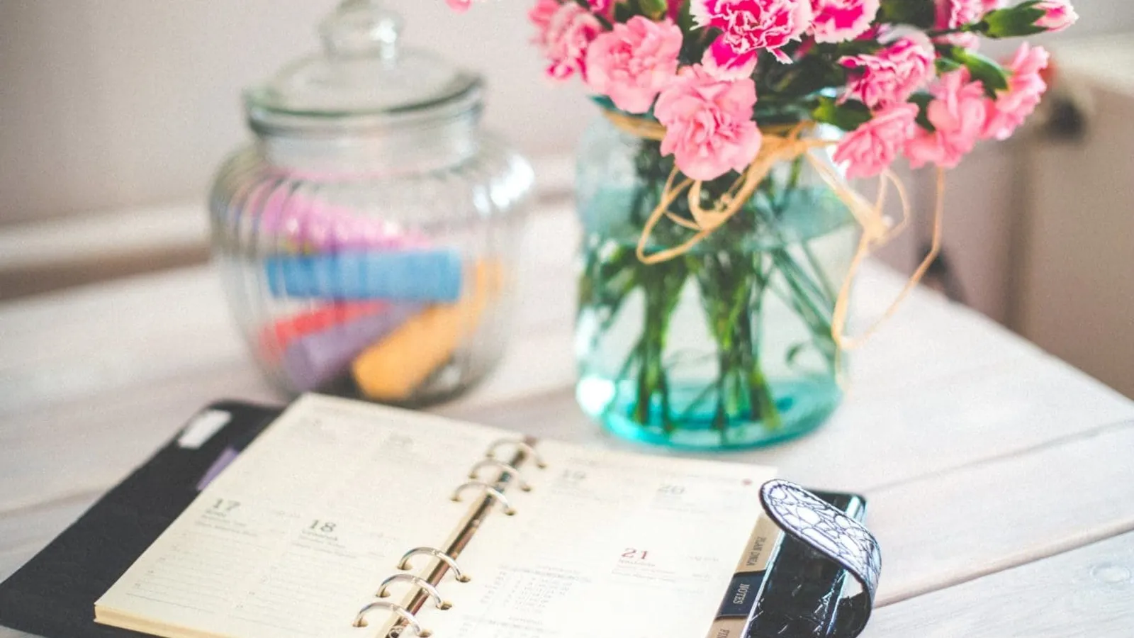 personal organizer and pink flowers on desk