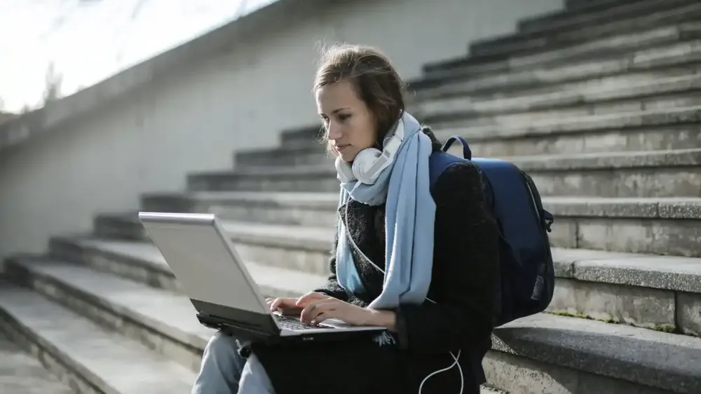 student with laptop on stairs