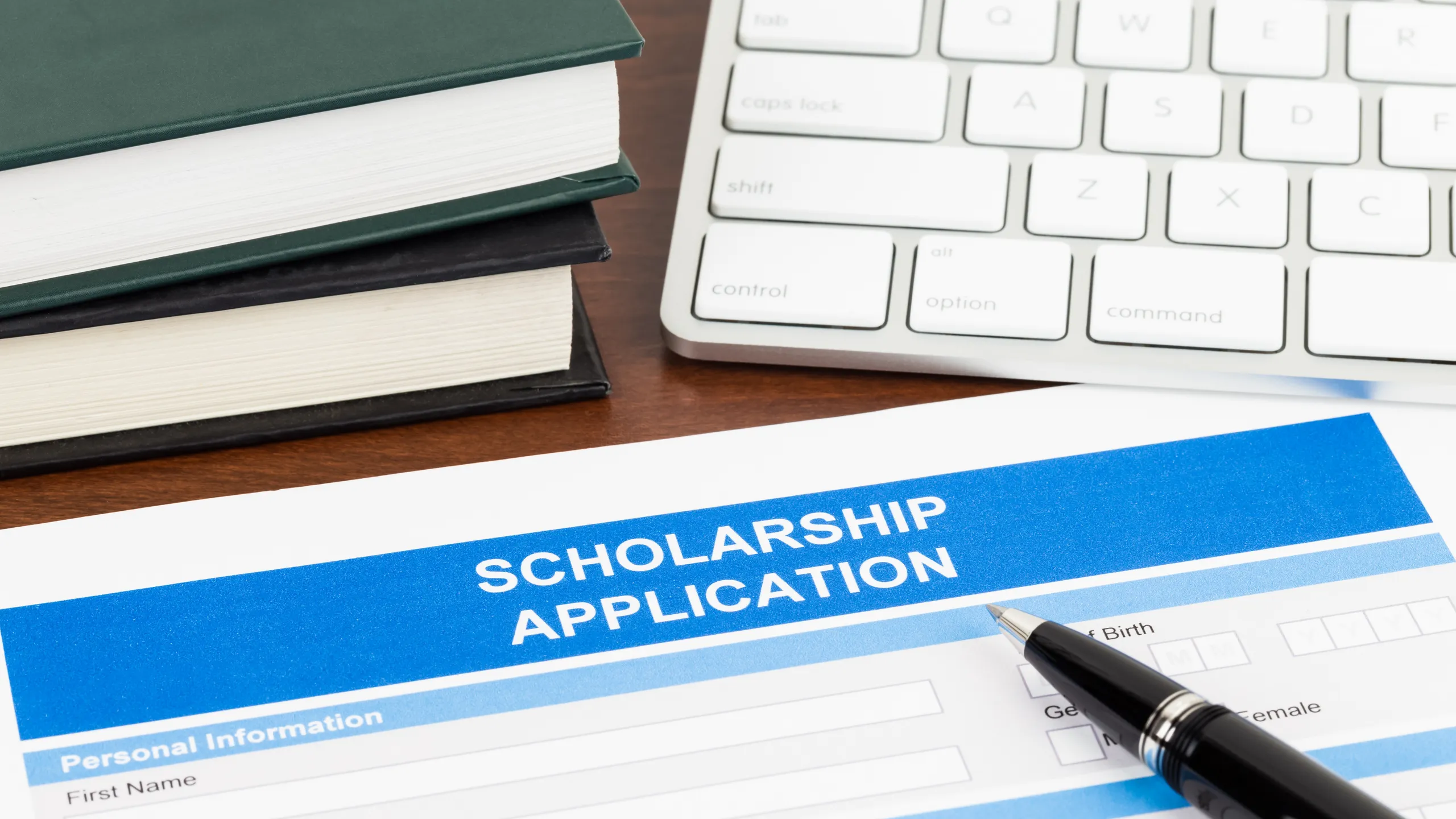 cholarship application form with pen, keyboard, and text book