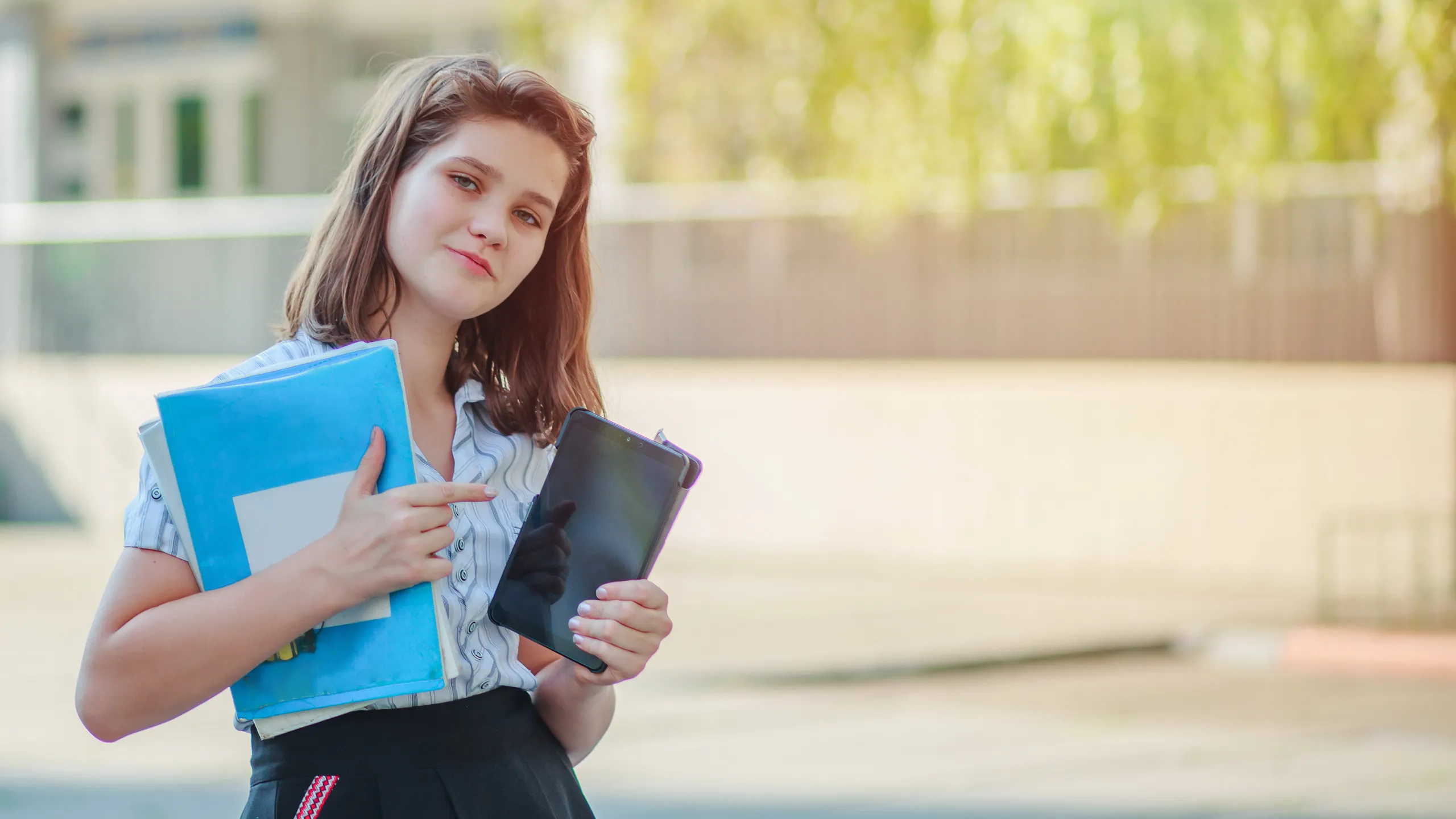 young girl holding tablet and textbooks