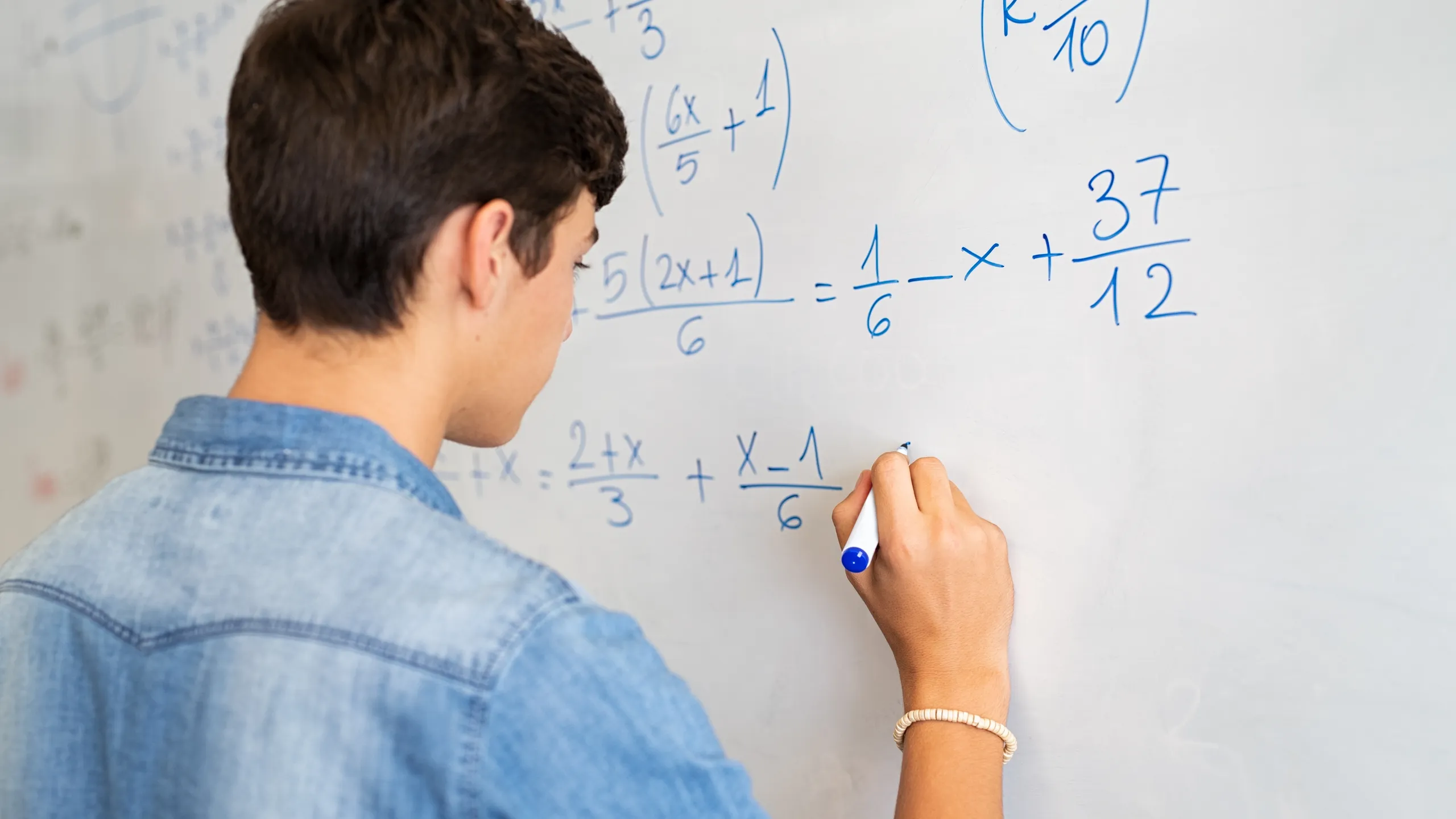 young student doing math on whiteboard