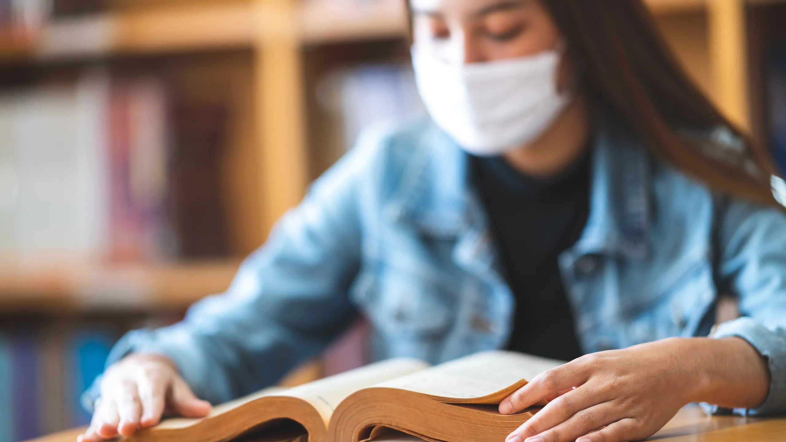 student wearing mask and reading at the library