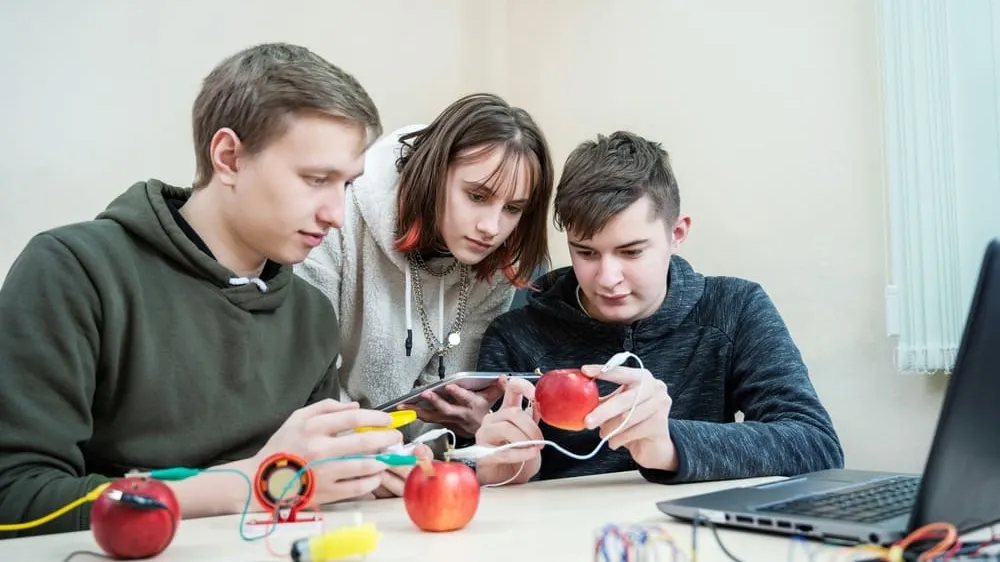students conduct a electricity experiment with apples