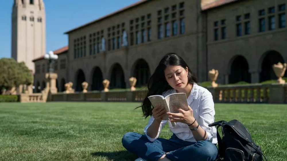 student reading a book on the grass